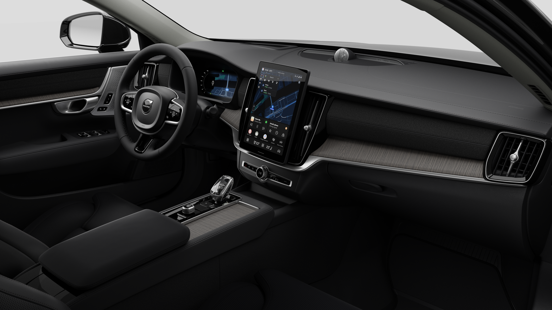 Interior view of a Volvo car showing the dashboard, steering wheel, center console, and digital display screen in a plain studio background.