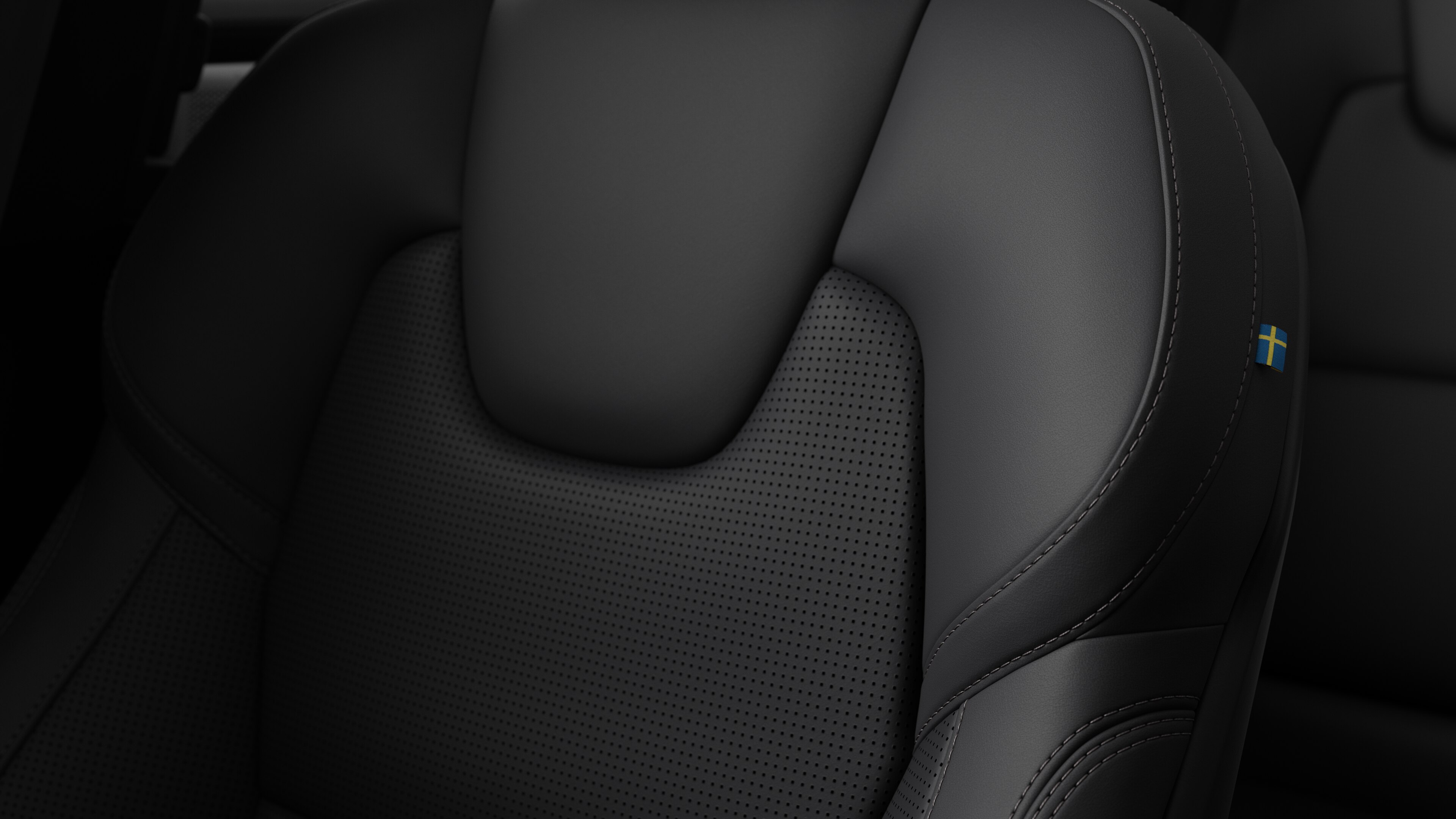 Close-up of Volvo car interior seat detail showing stitching and a small Swedish flag tag.