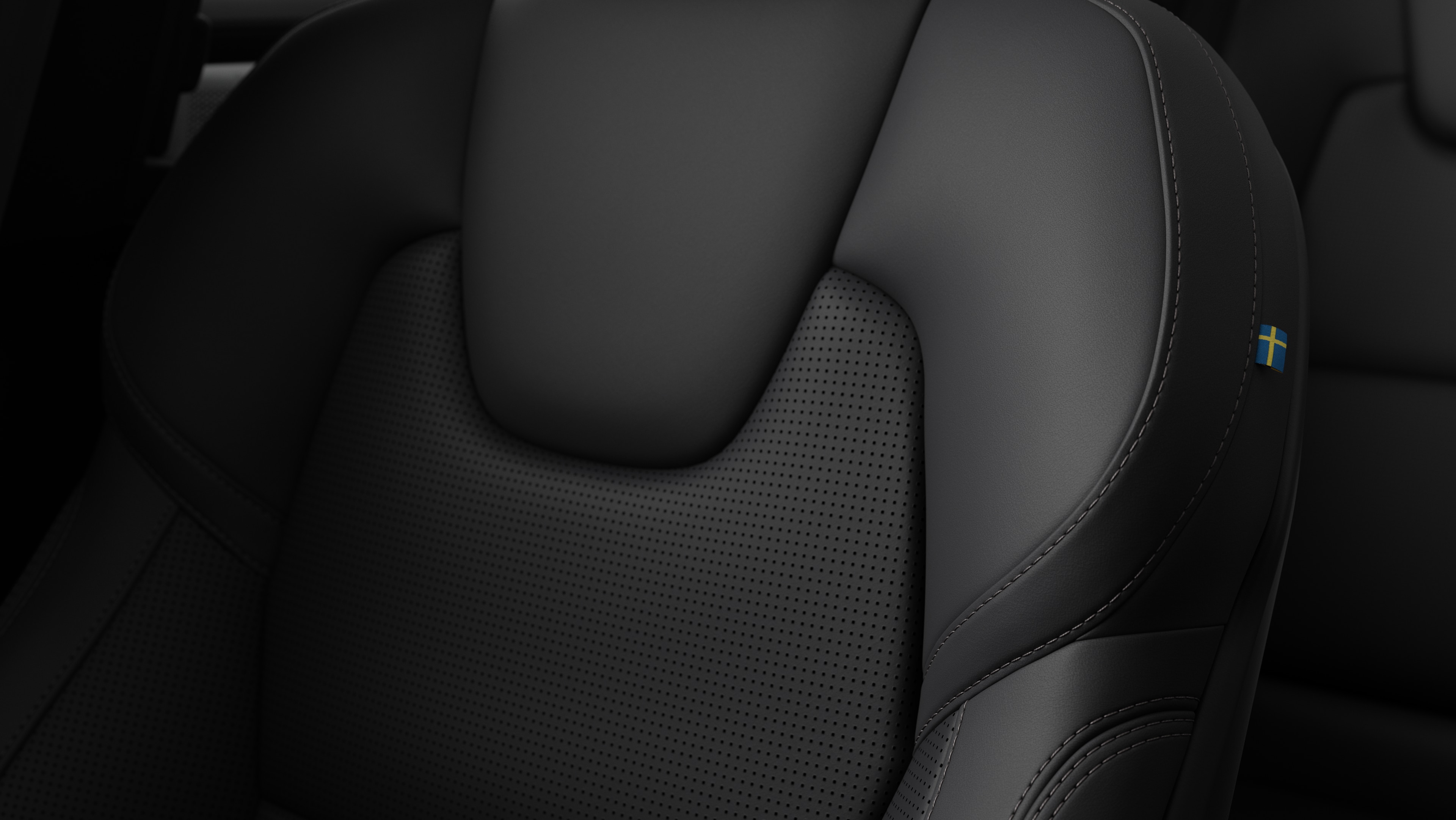 Close-up of Volvo car interior seat detail showing stitching and a small Swedish flag tag.