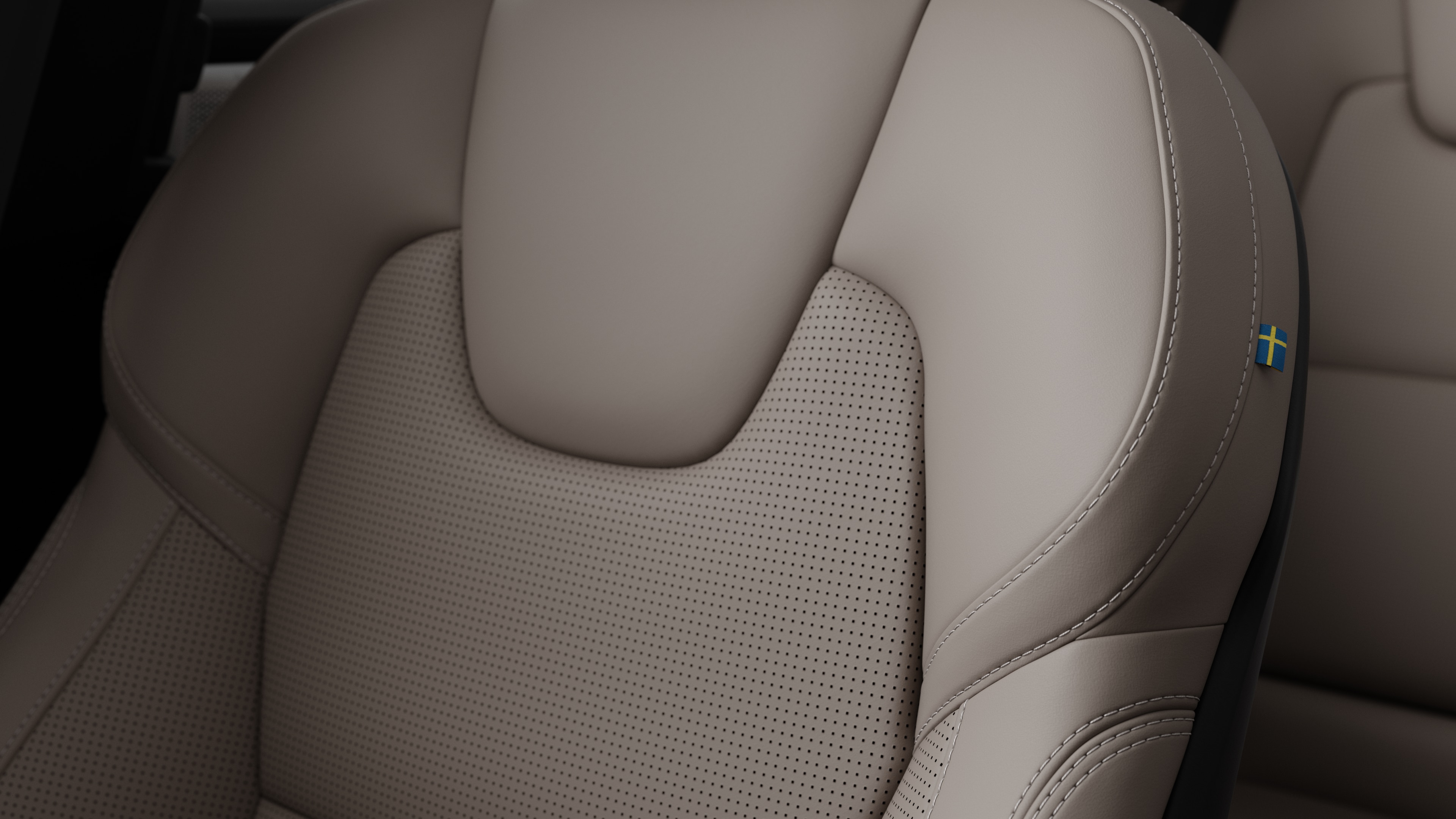 Close-up of Volvo car interior seat detail showing stitching and a small Swedish flag tag.