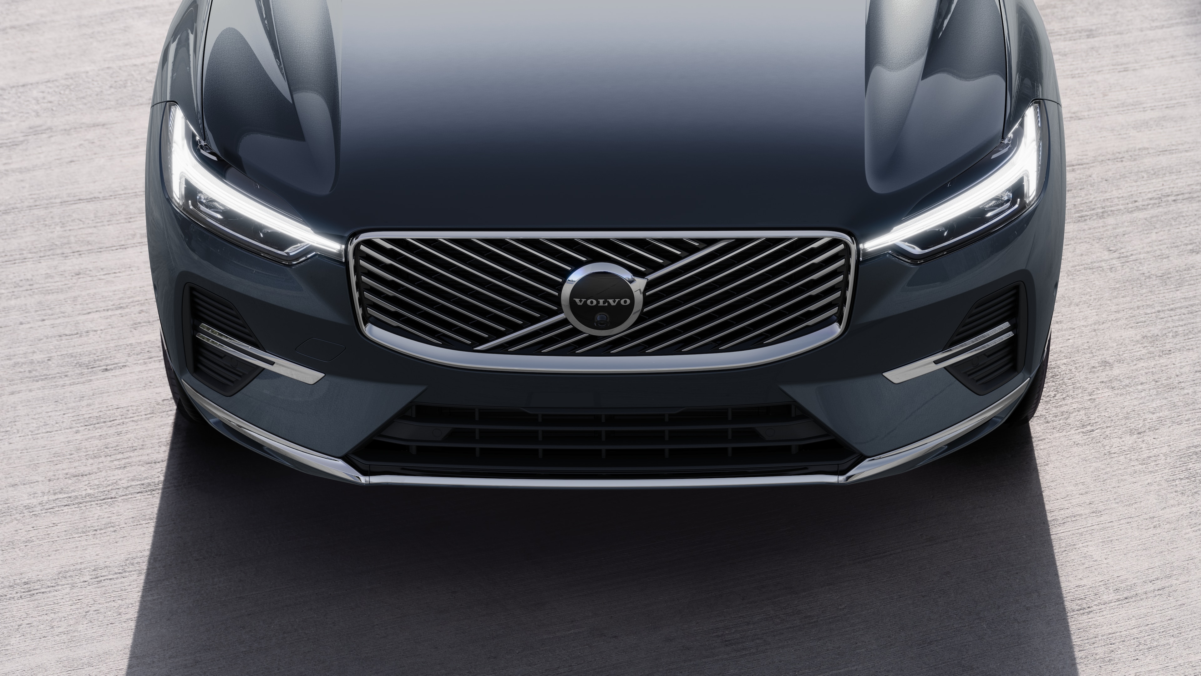 볼보 자동차 외관은 도시 거리 배경에서 3/4 뷰로 한쪽 면, 지붕 및 전면 일부를 보여줍니다.