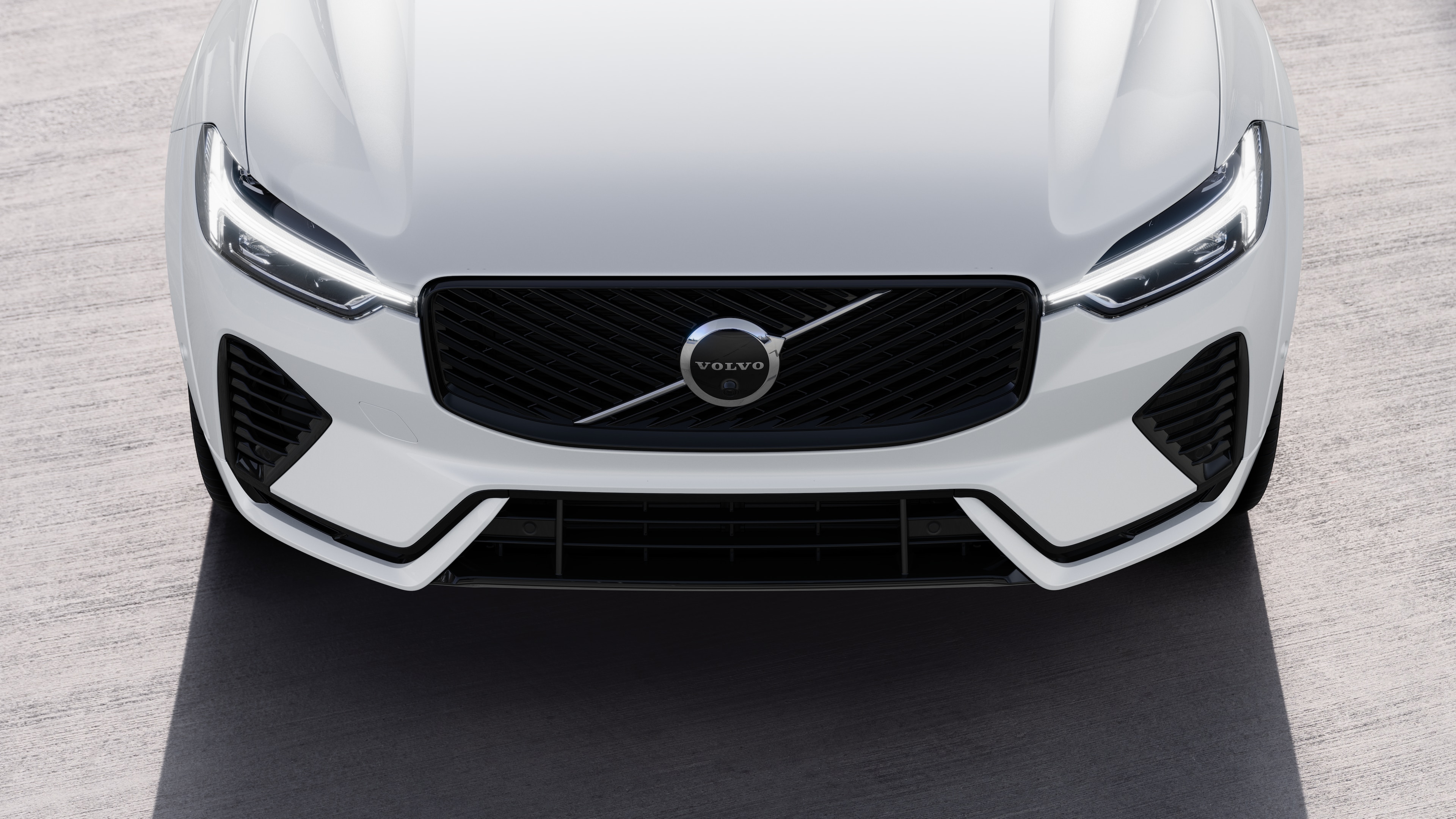 Exterior do carro Volvo em vista de três quartos em um fundo de rua urbana, mostrando um lado, teto e parte da frente.