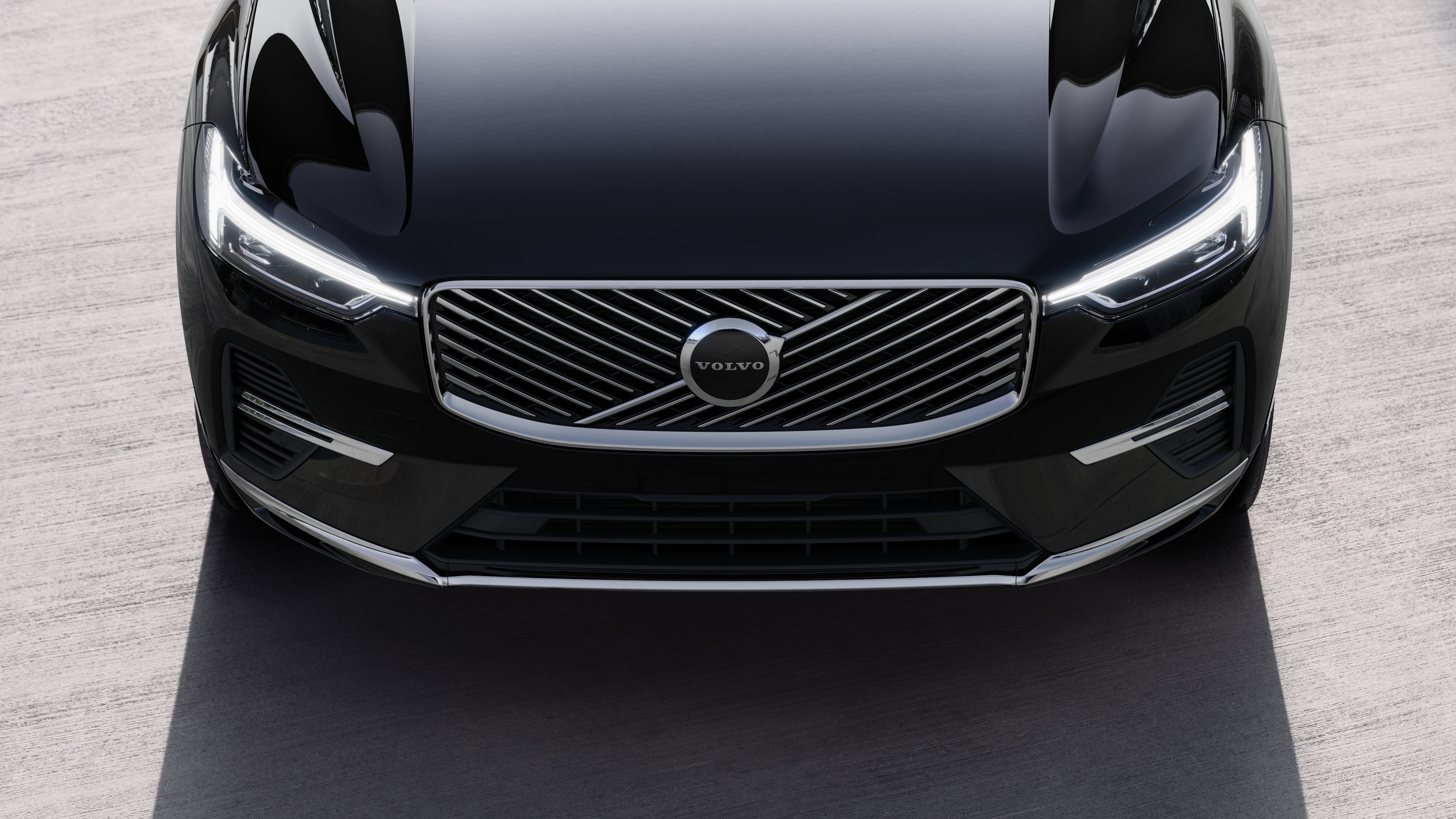 Το εξωτερικό ενός αυτοκινήτου Volvo σε άποψη τριών τετάρτων σε αστικό φόντο, όπου φαίνεται η μία πλευρά, η οροφή και μέρος του εμπρός.