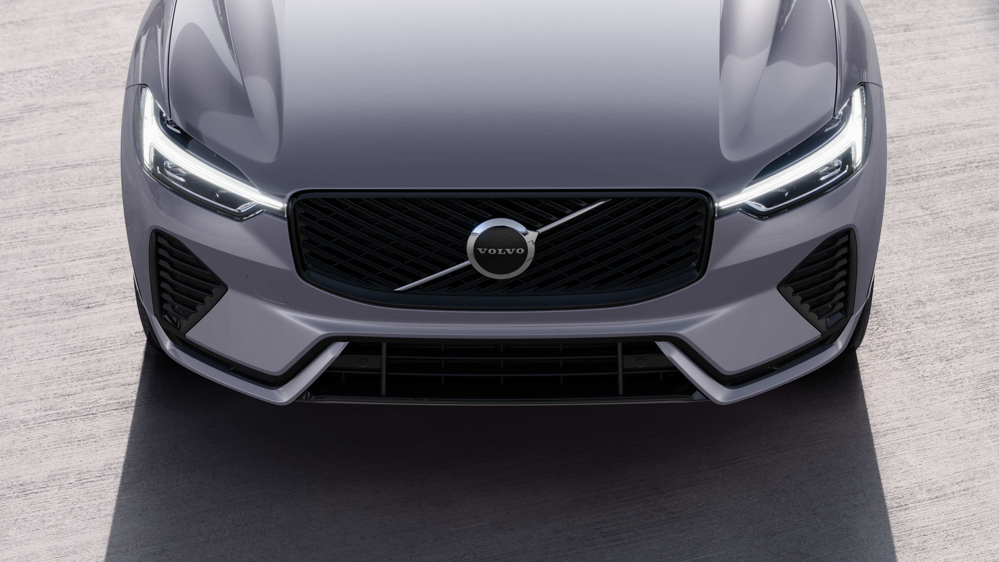 Volvo automašīnas ārpuse trīs ceturtdaļu skatā uz pilsētas ielas fona, parādot vienu pusi, jumtu un daļu priekšpuses.