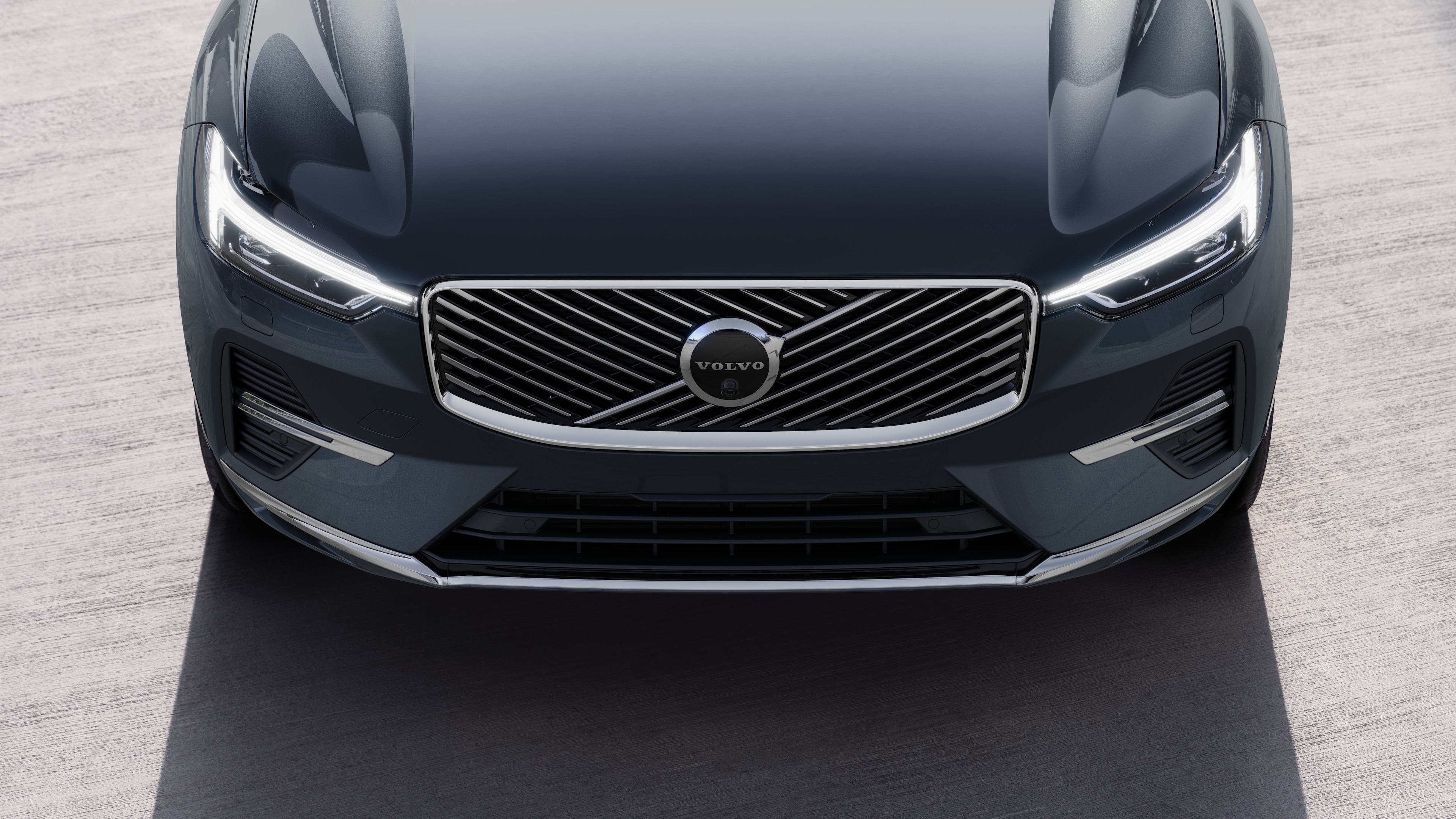 Kentsel bir cadde arka planında bir tarafı, tavanı ve ön kısmın bir kısmını gösteren üç çeyrek görünümde Volvo otomobilin dış görünümü.