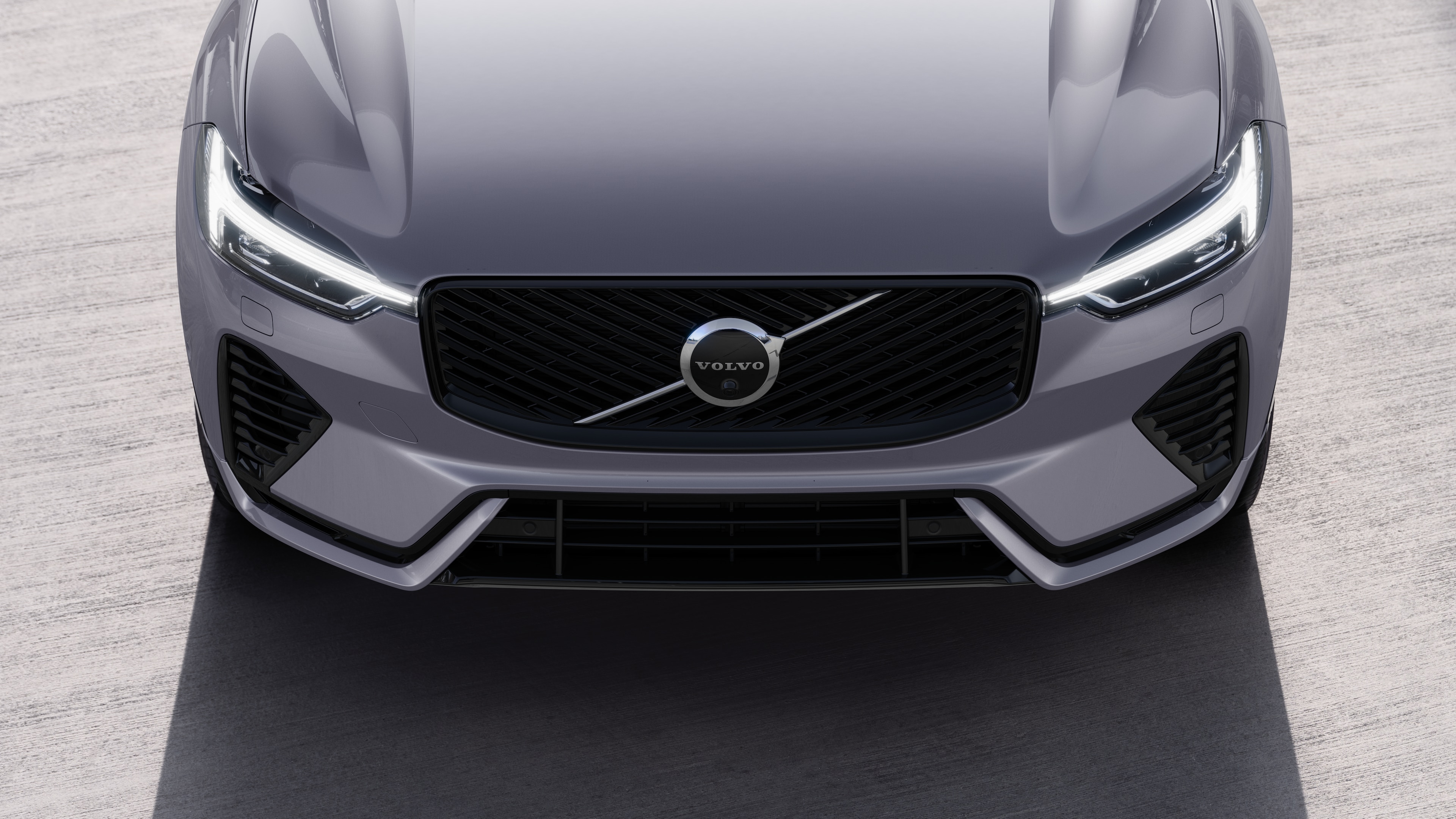 Pjesa e jashtme e makinës Volvo në pamje tre të katërtat në një sfond të rrugës urbane, duke treguar njërën anë, çati dhe një pjesë të pjesës së përparme.