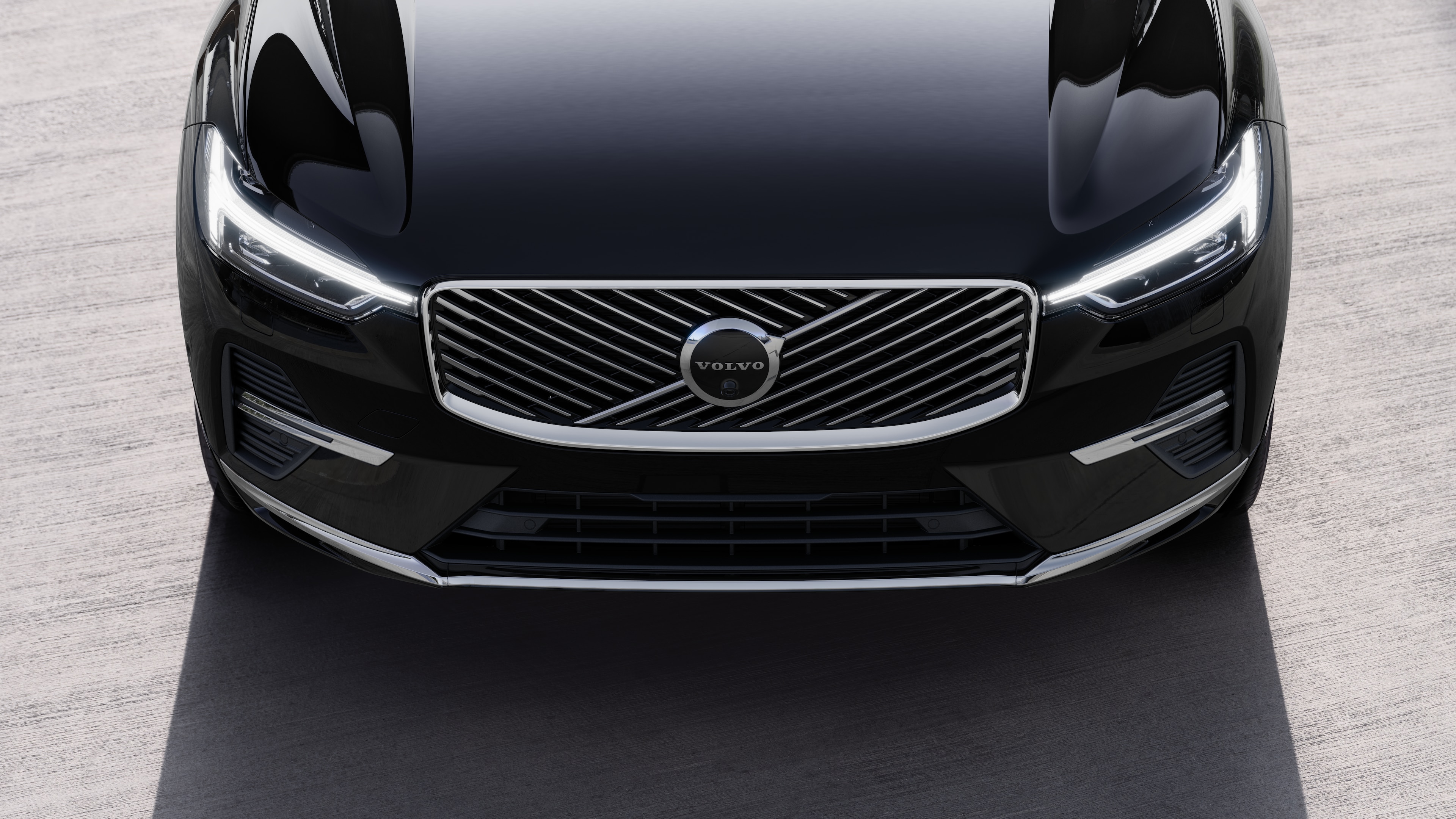 Kentsel bir cadde arka planında bir tarafı, tavanı ve ön kısmın bir kısmını gösteren üç çeyrek görünümde Volvo otomobilin dış görünümü.