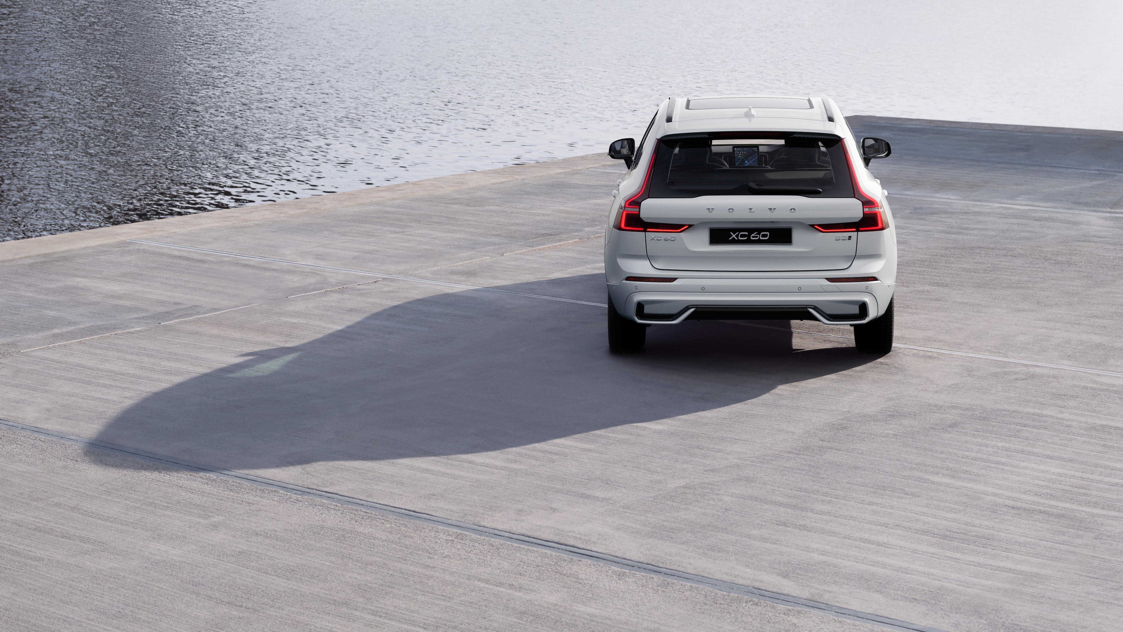 Volvo car rear view on a winding coastal road with a beachside background.
