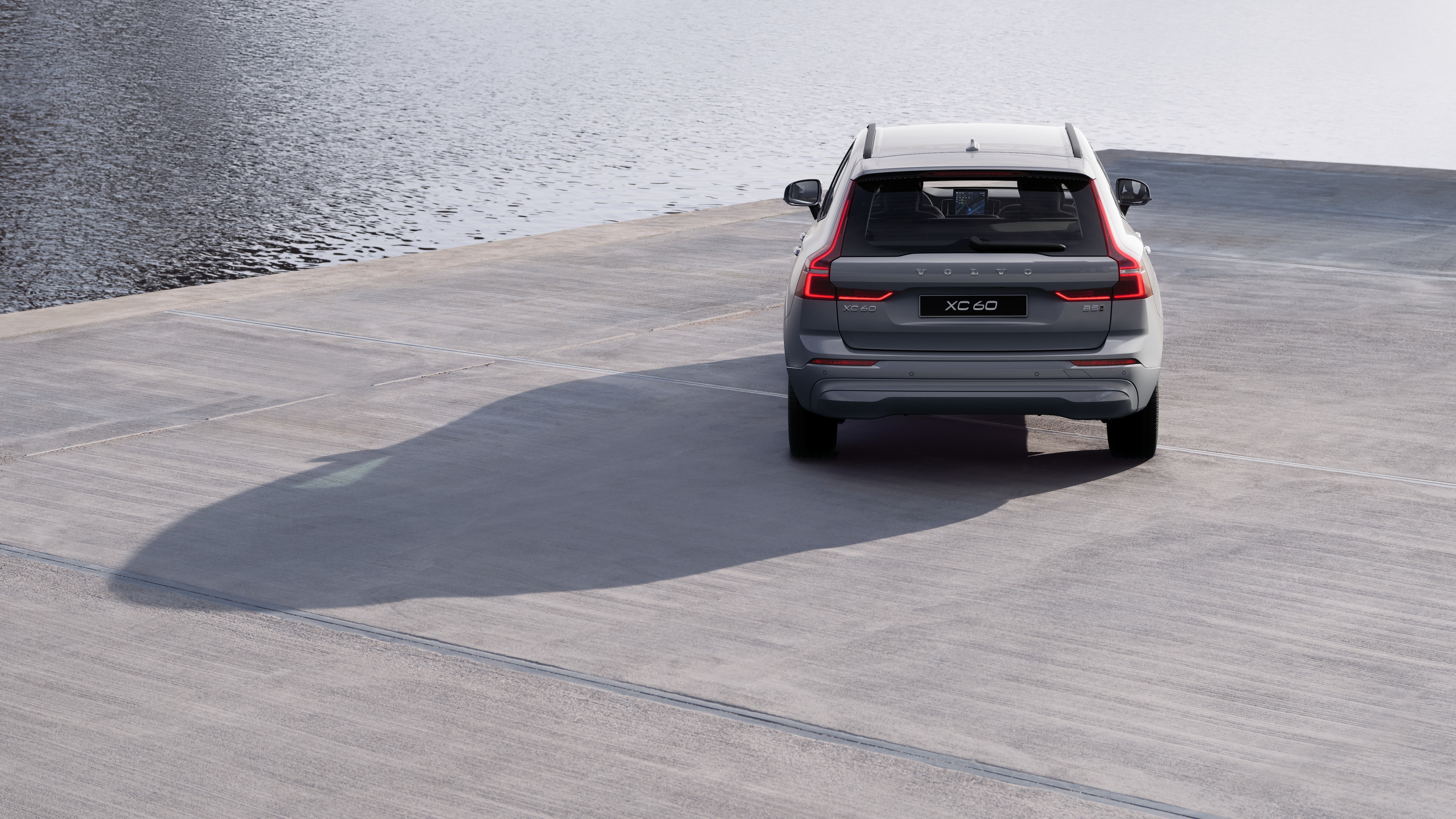 Heckansicht eines Volvo auf einer kurvigen Küstenstraße mit Strandhintergrund.