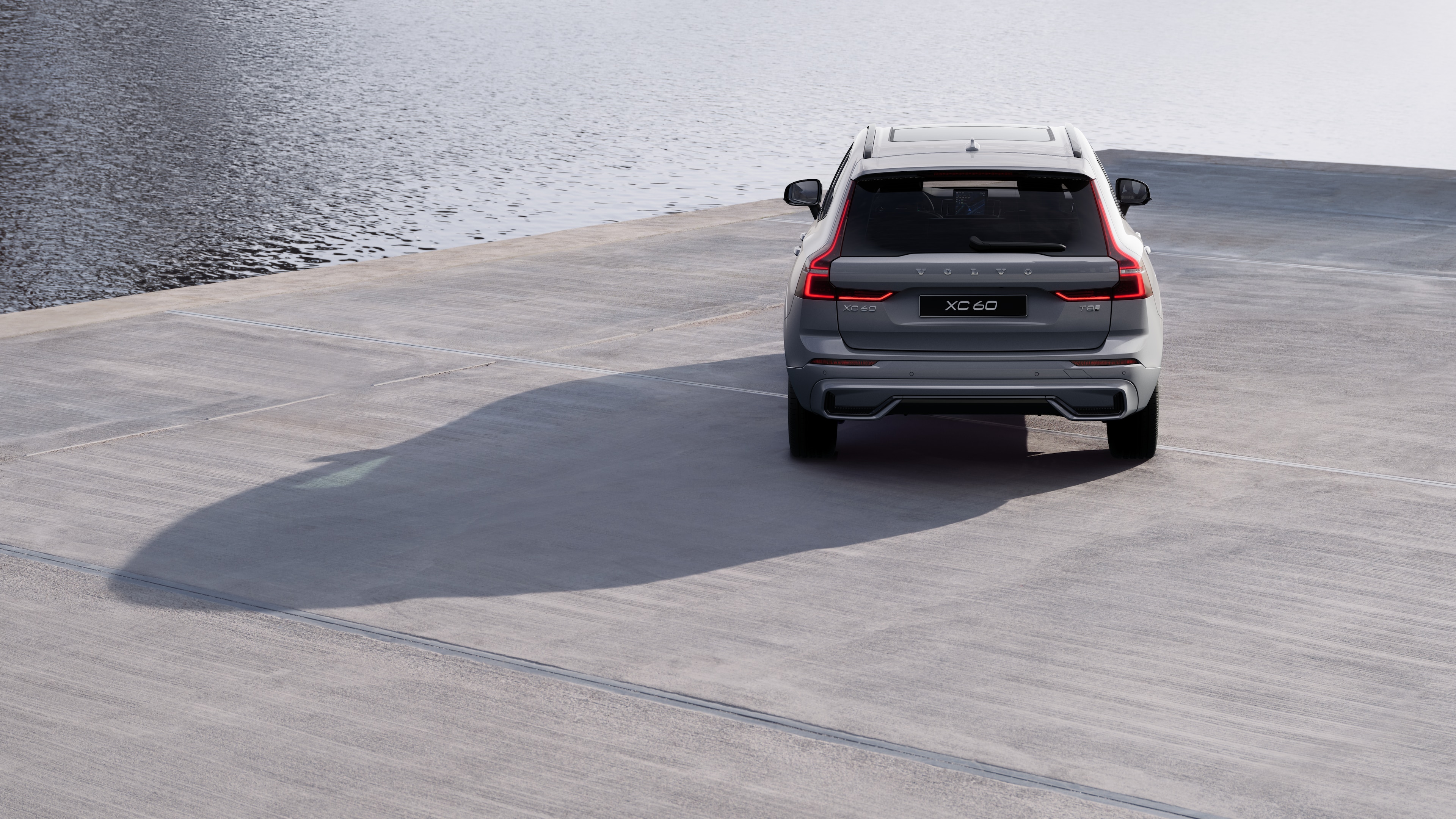 Volvo car rear view on a winding coastal road with a beachside background.