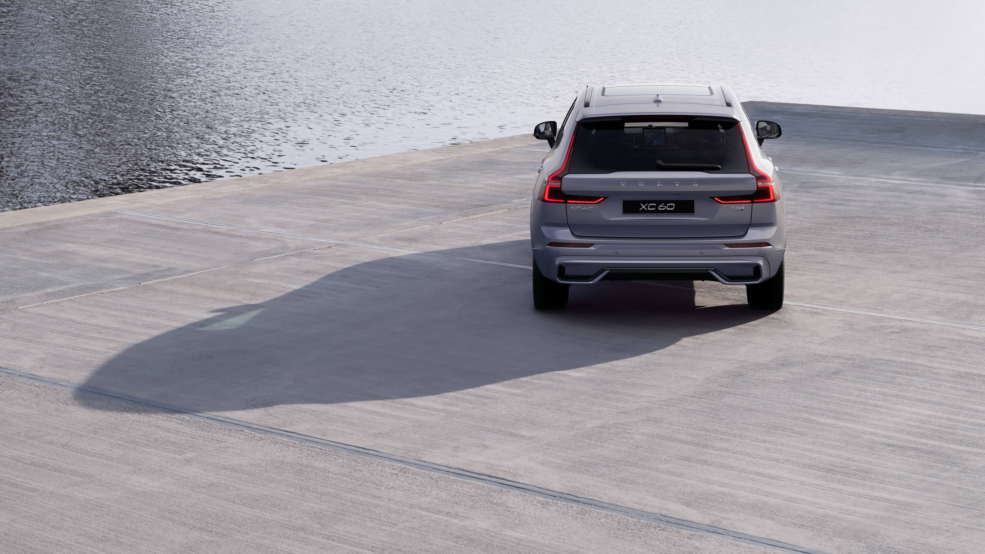 Volvo car rear view on a winding coastal road with a beachside background.