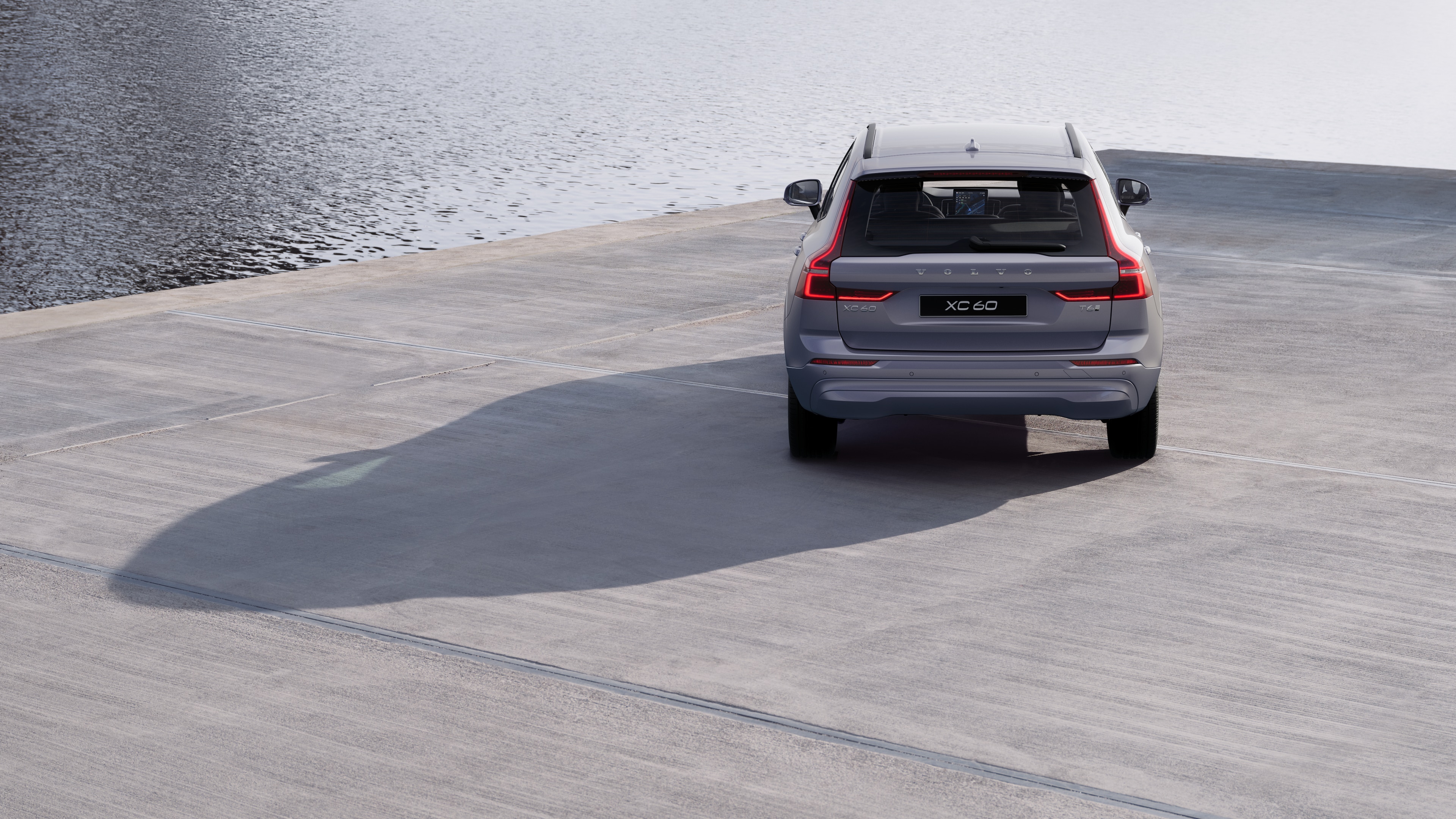 Achteraanzicht van een Volvo op een kronkelende kustweg met een strandachtergrond.
