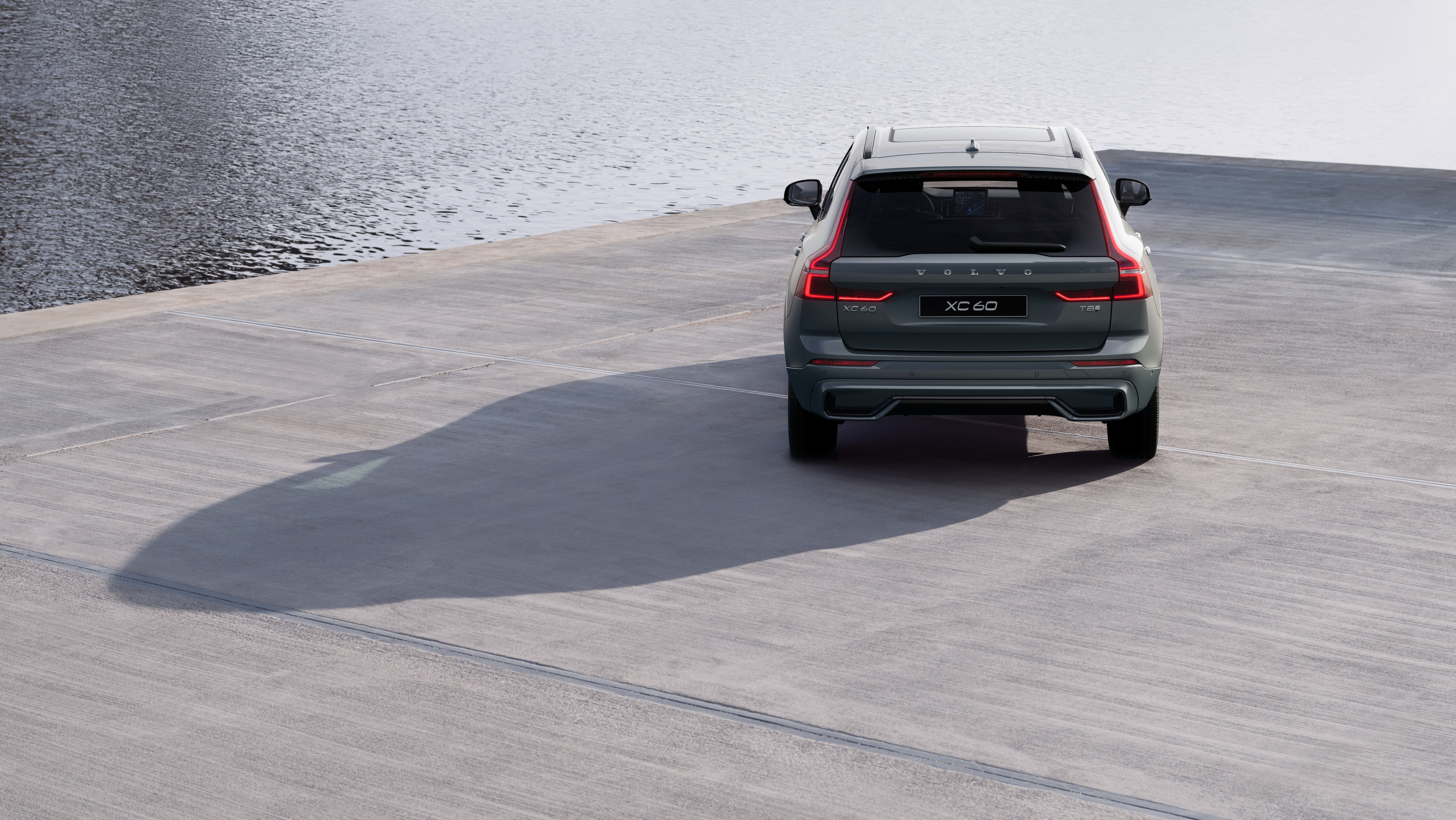 Volvo car rear view on a winding coastal road with a beachside background.