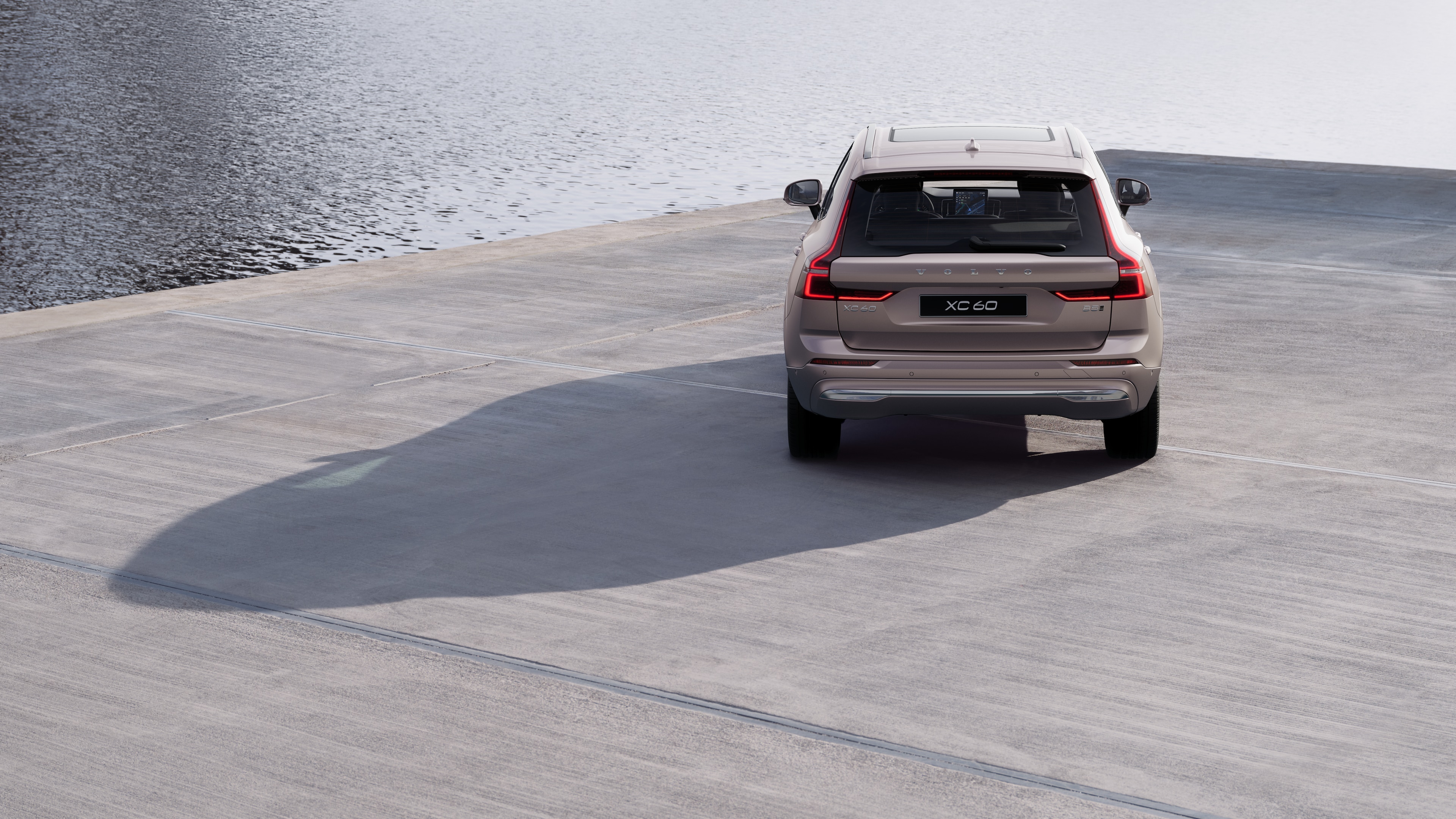 Vista posteriore di un'auto Volvo su una tortuosa strada costiera con sfondo sulla spiaggia.