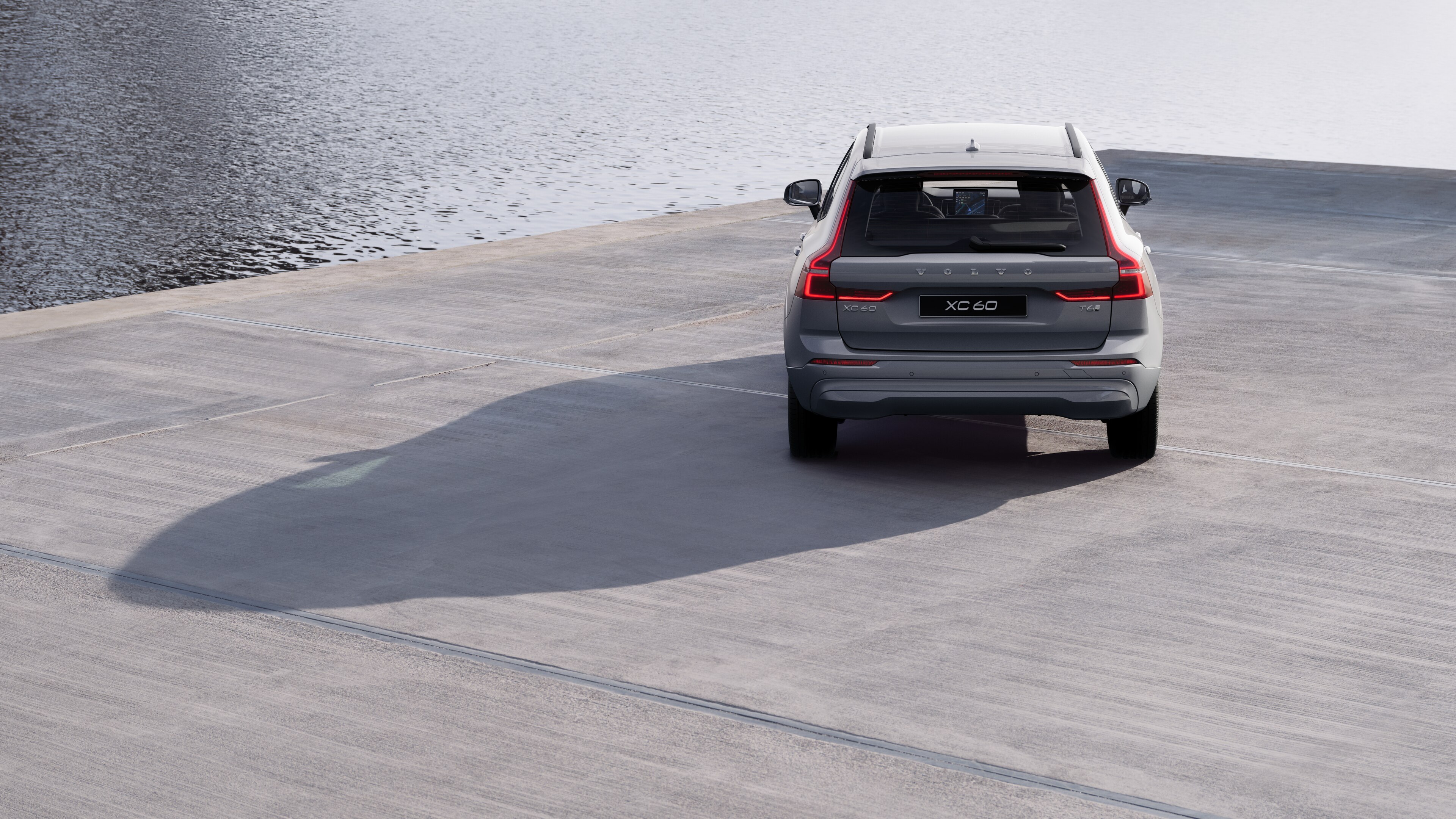 Heckansicht eines Volvo auf einer kurvigen Küstenstraße mit Strandhintergrund.