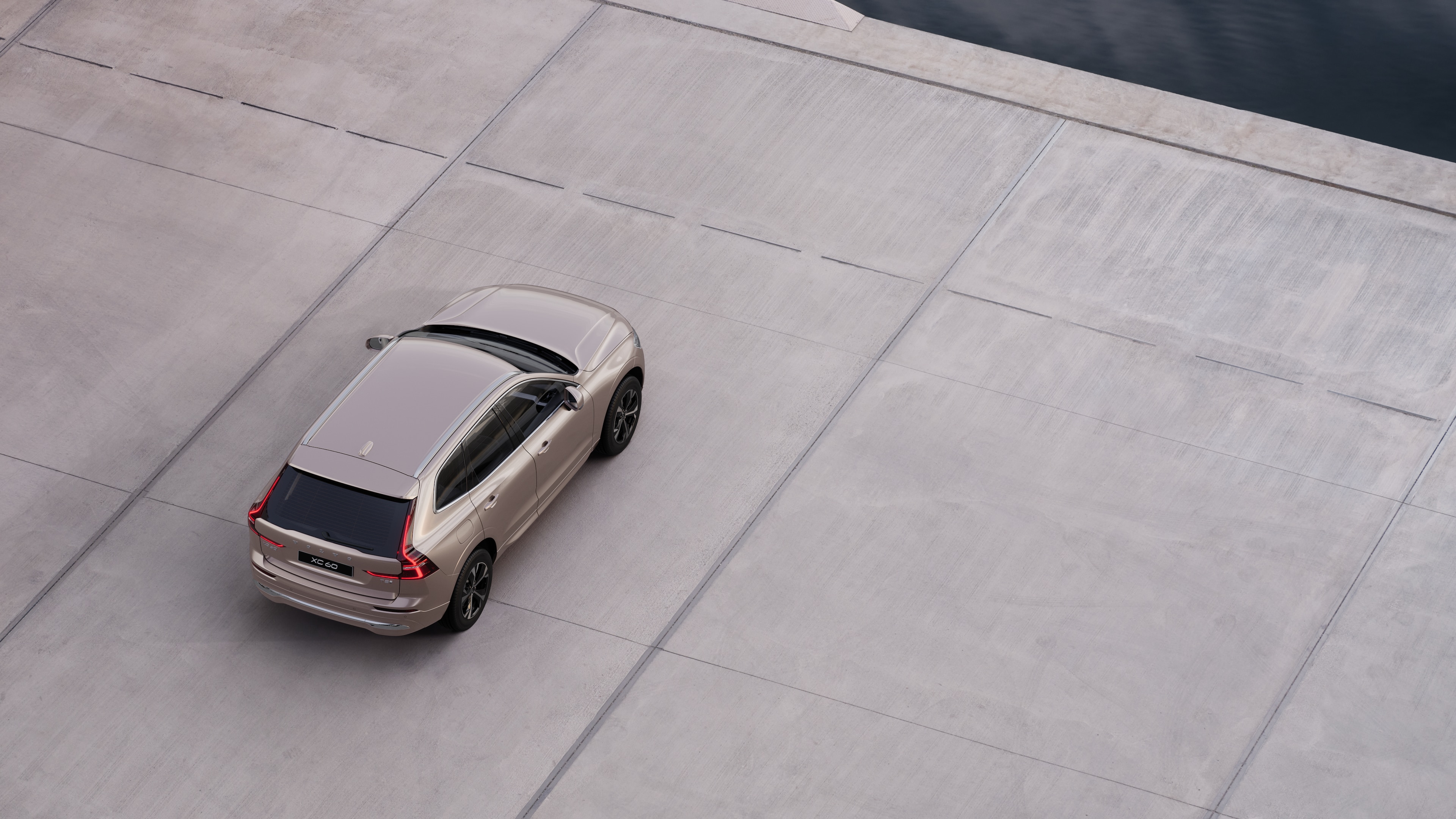 Vue arrière d’une Volvo garée dans une rue calme au bord de l’eau, avec une allée pavée et de l’eau en arrière-plan.