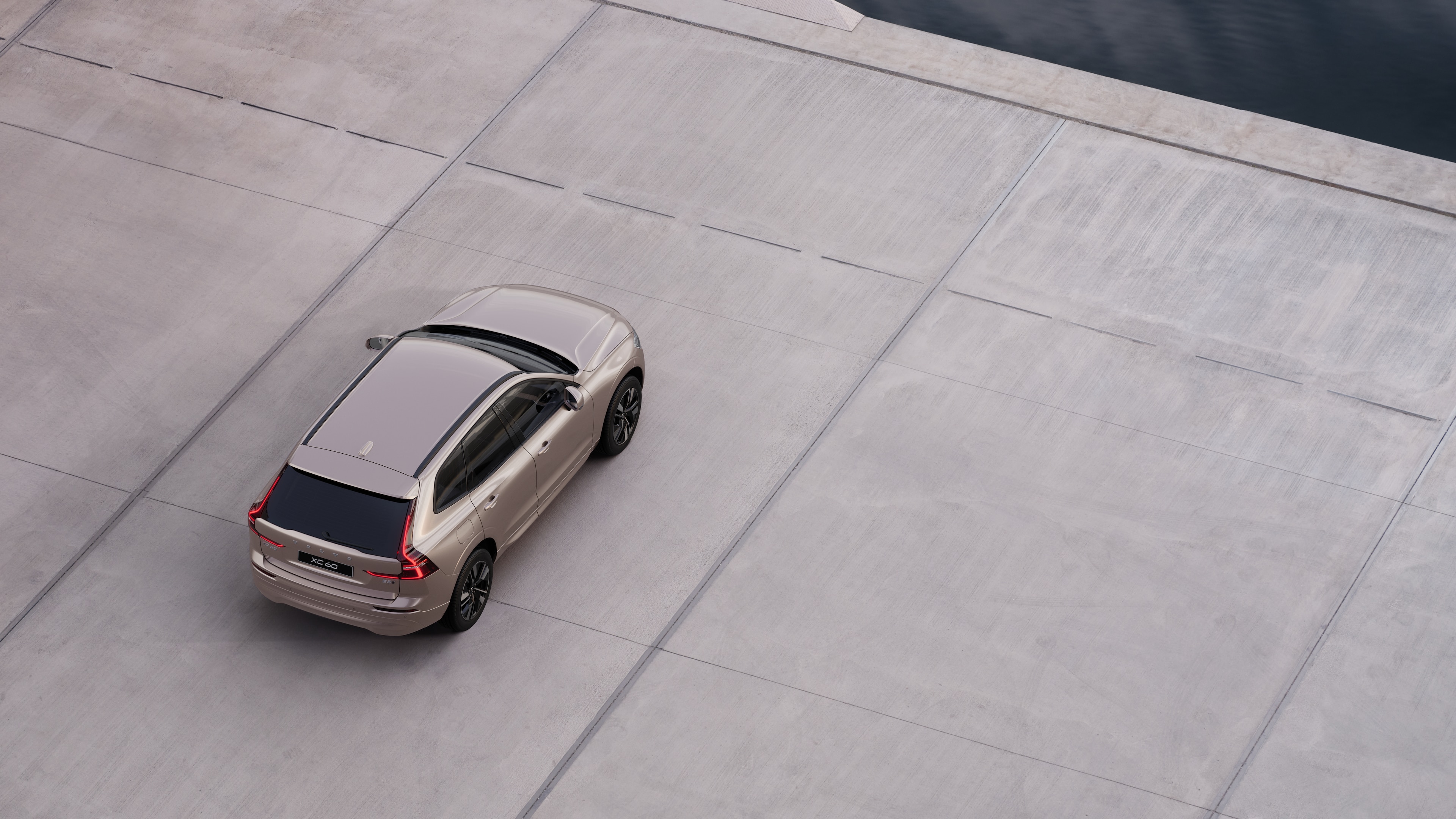 מבט מאחור על מכונית וולוו חונה ברחוב שקט ליד מים, עם שביל סלול ומים ברקע.