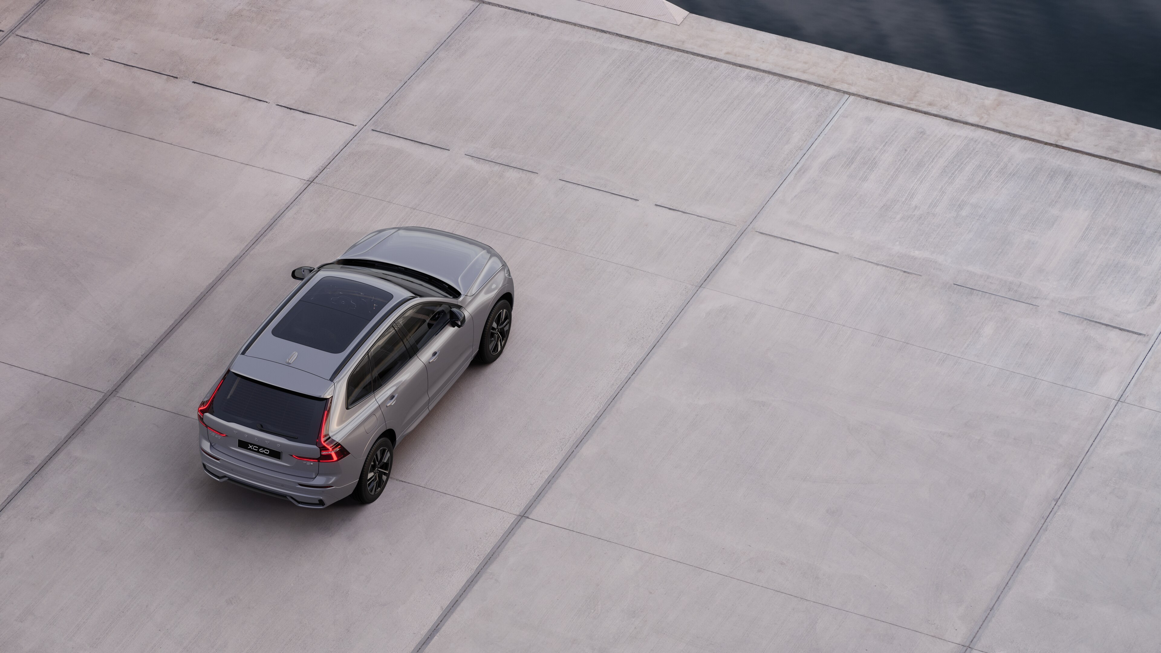 Vue arrière d’une Volvo garée dans une rue calme au bord de l’eau, avec une allée pavée et de l’eau en arrière-plan.