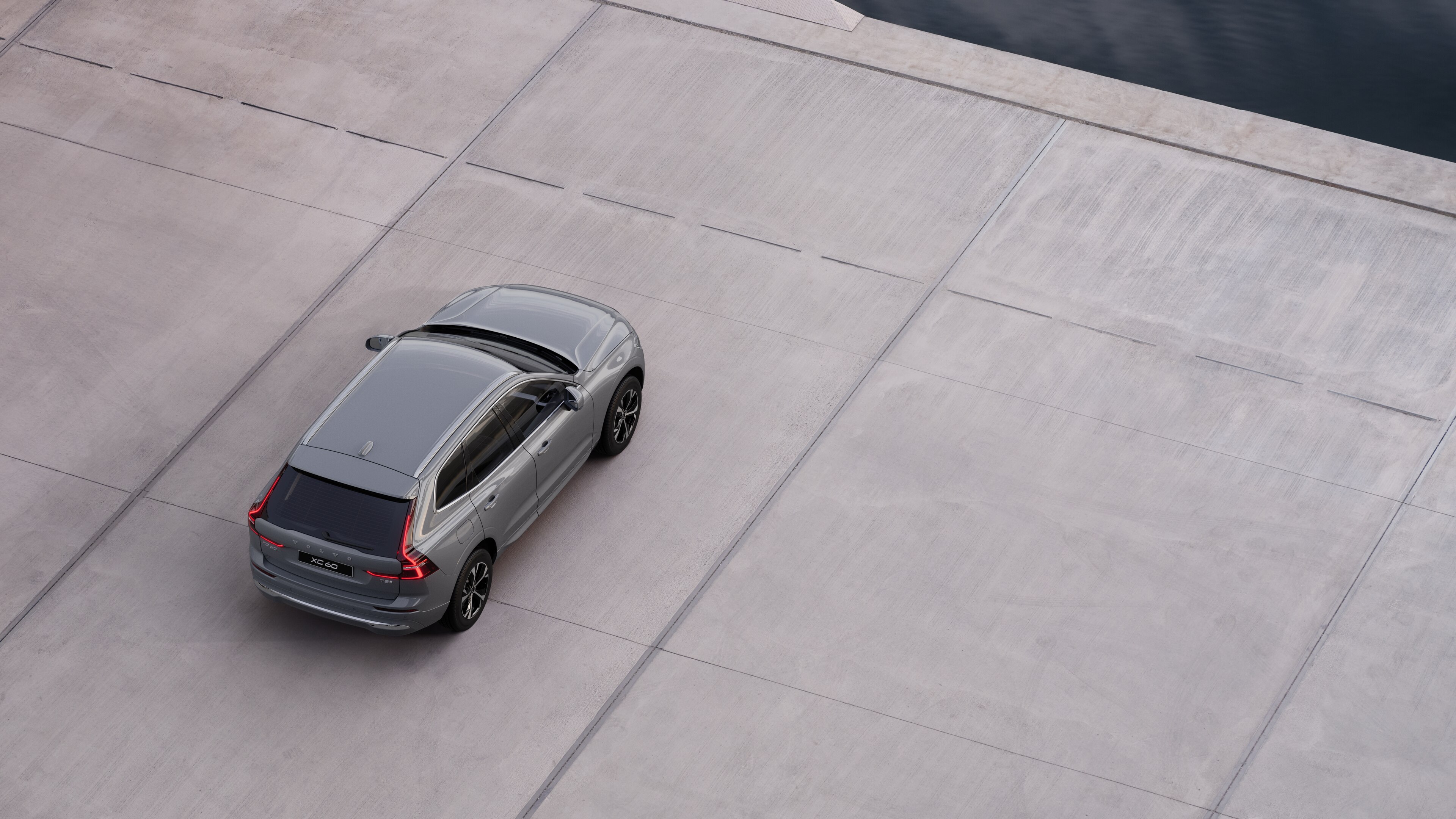 Vue arrière d’une Volvo garée dans une rue calme au bord de l’eau, avec une allée pavée et de l’eau en arrière-plan.