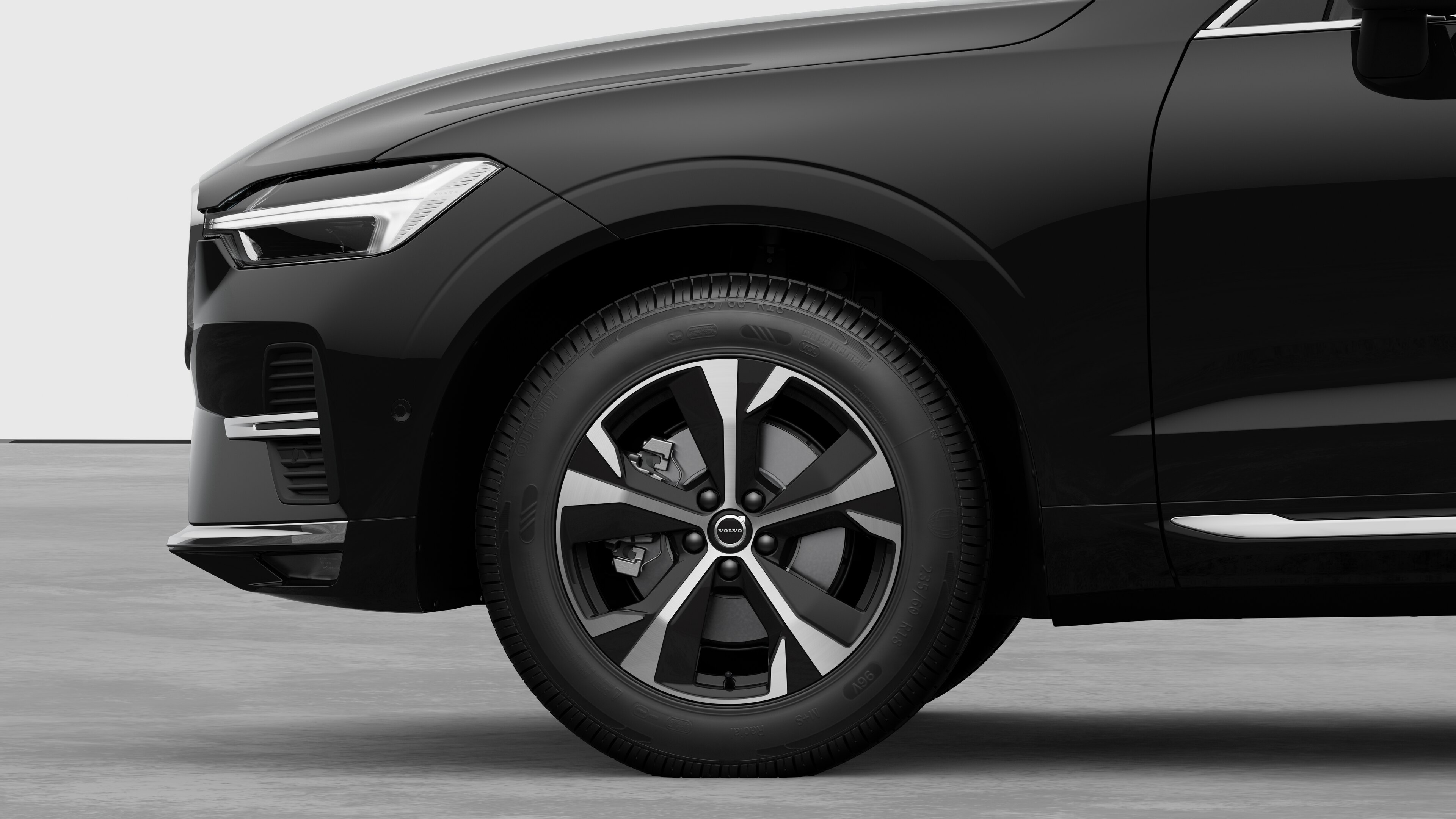 無地のスタジオを背景に、フロントホイールとフェンダーに焦点を合わせたボルボ車のエクステリアサイドビュー。