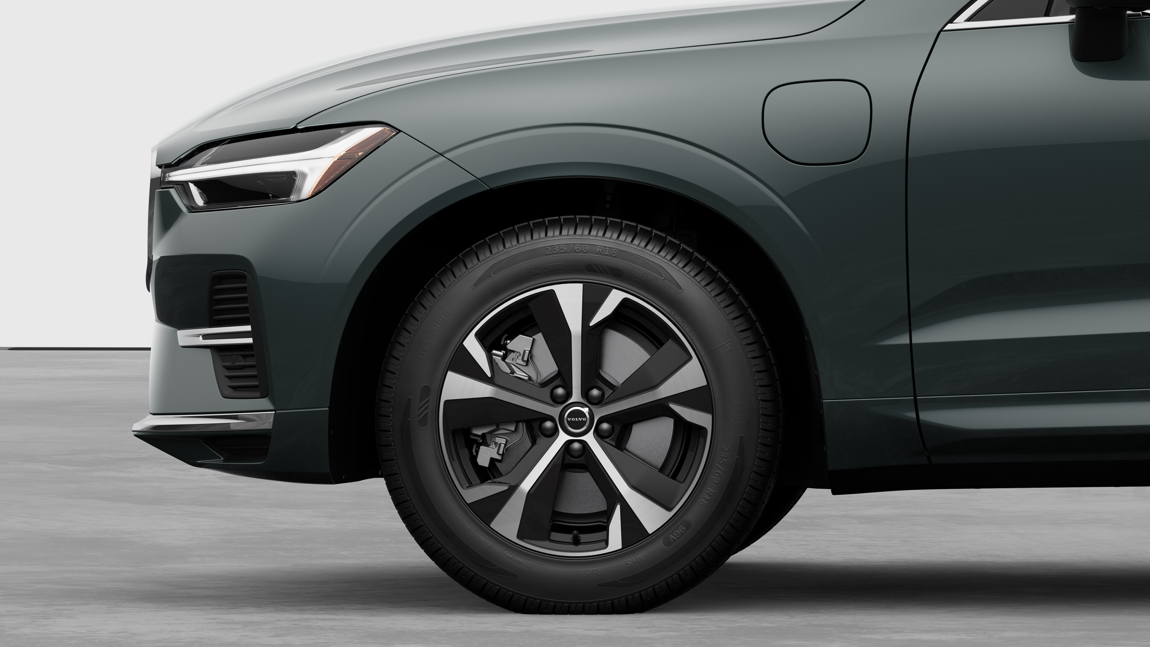 Vista lateral exterior del vehículo Volvo centrada en la rueda delantera y el guardabarros, sobre un fondo de estudio liso.