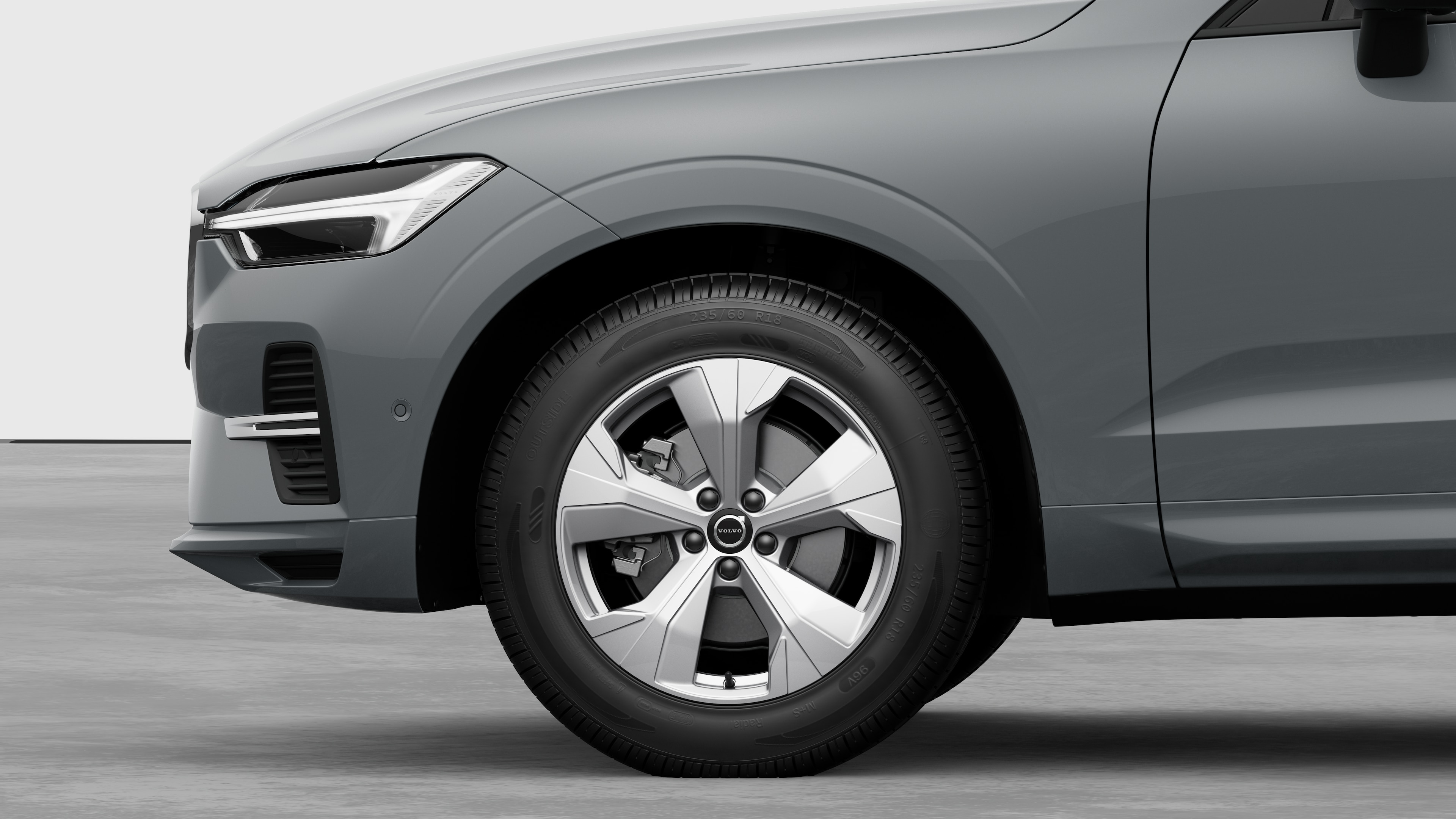 Volvo car exterior side view focusing on the front wheel and fender, set against a plain studio background.