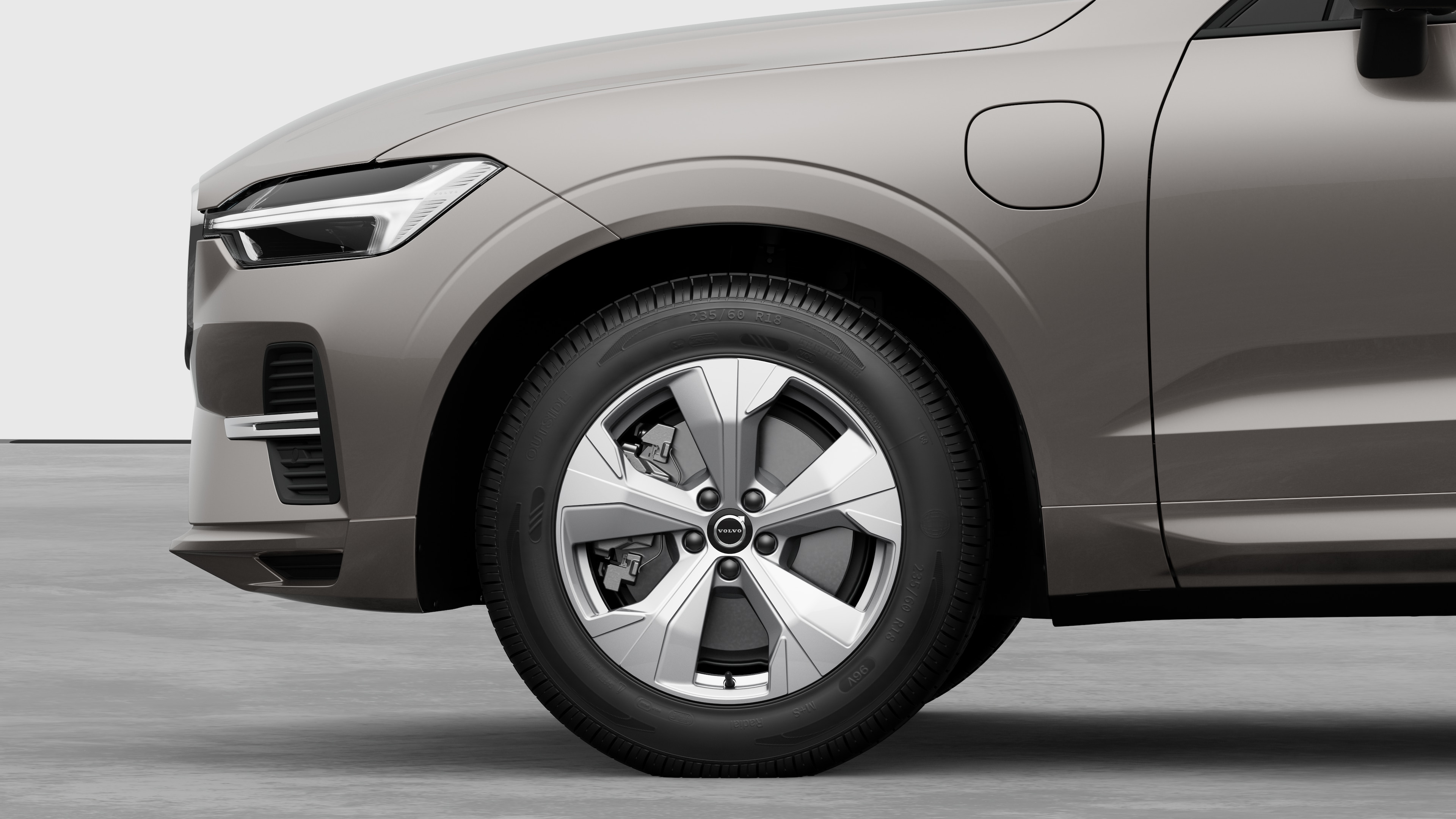 Vista laterale esterna di una Volvo con focus sulla ruota anteriore e sul parafango, su uno sfondo semplice in studio.