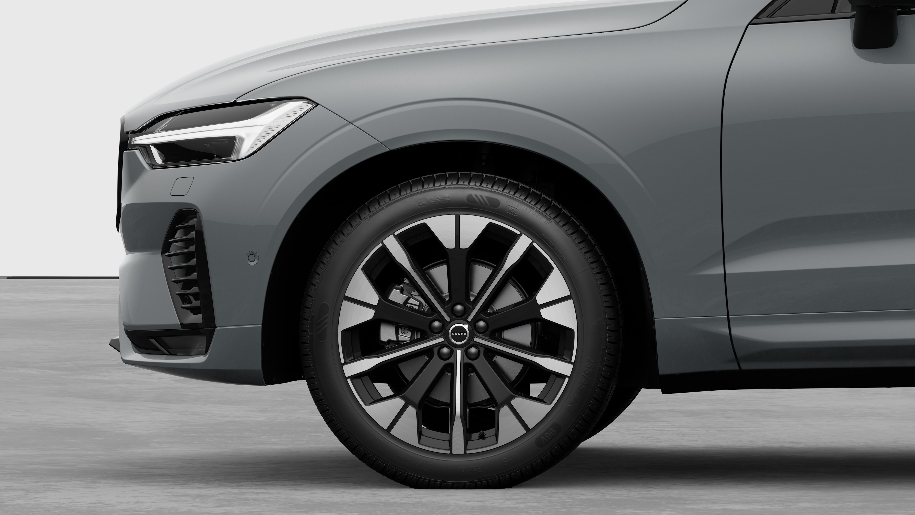 Widok boczny z zewnątrz samochodu Volvo, skupiający się na przednim kole i błotniku, na tle zwykłego studia