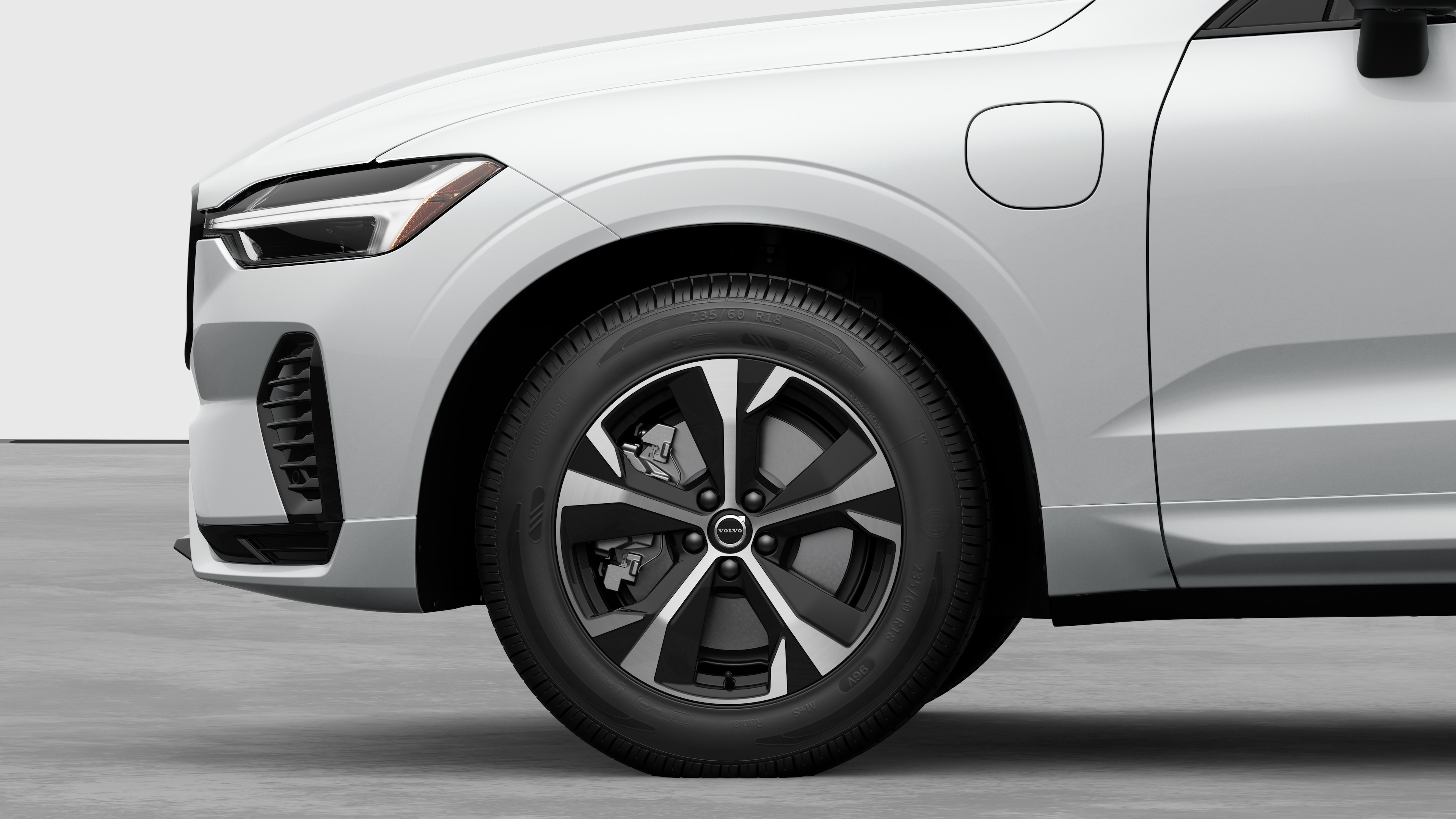 Vue latérale de l’extérieur d’une voiture Volvo, avec l’accent mis sur la roue avant et l’aile, sur un fond de studio uni.