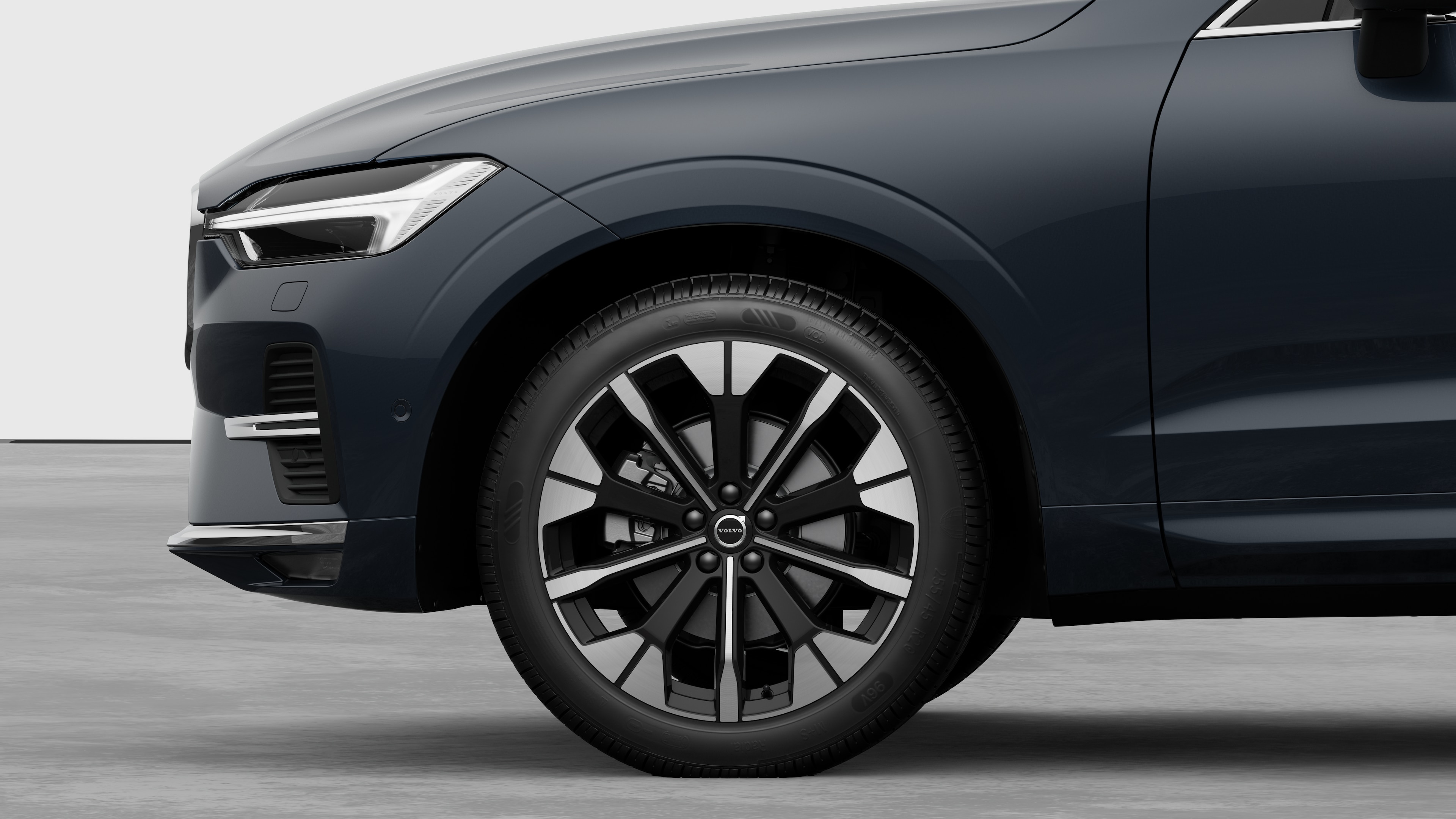 Vista laterale esterna di una Volvo con focus sulla ruota anteriore e sul parafango, su uno sfondo semplice in studio.