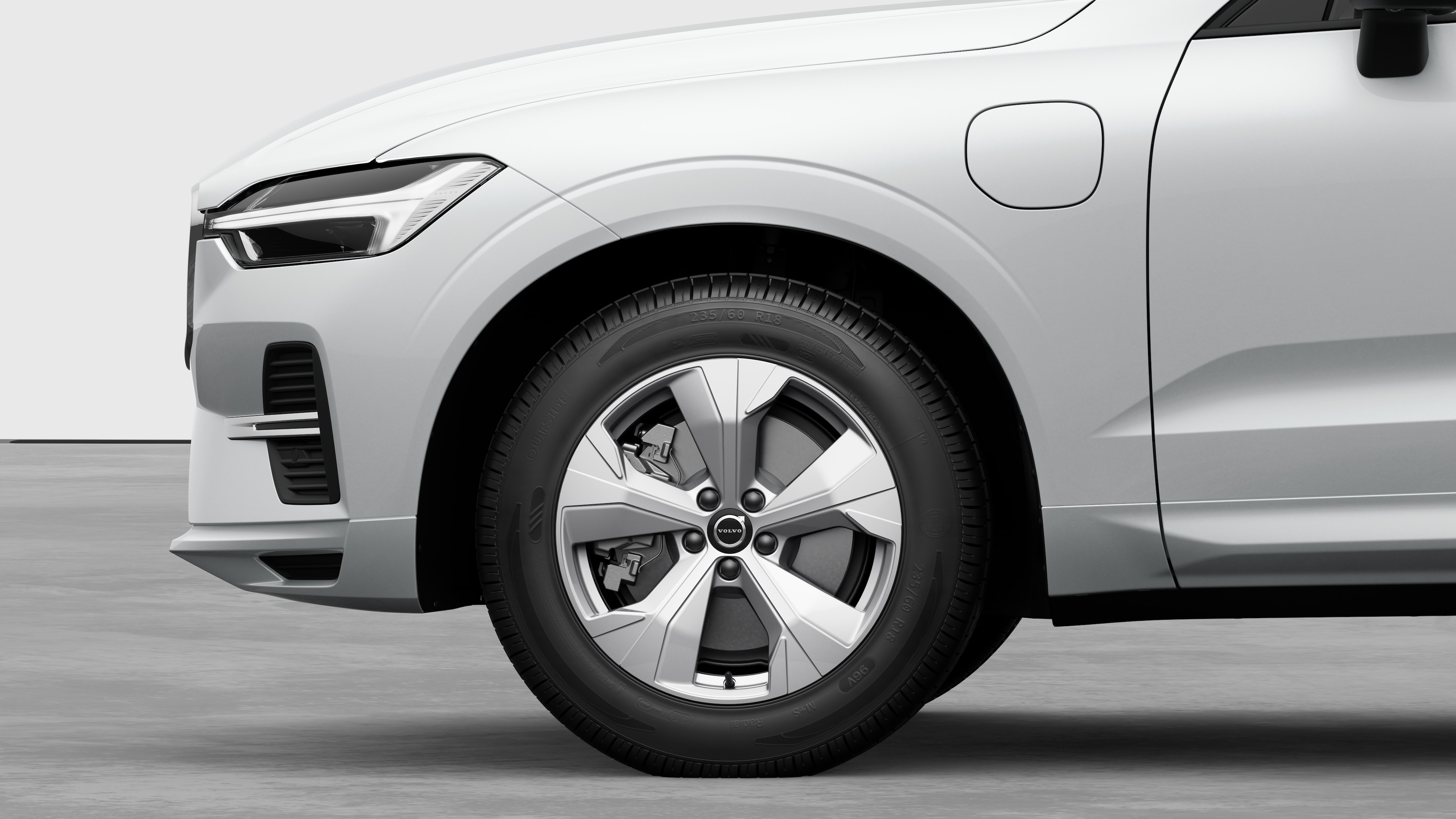 Vista laterale esterna di una Volvo con focus sulla ruota anteriore e sul parafango, su uno sfondo semplice in studio.