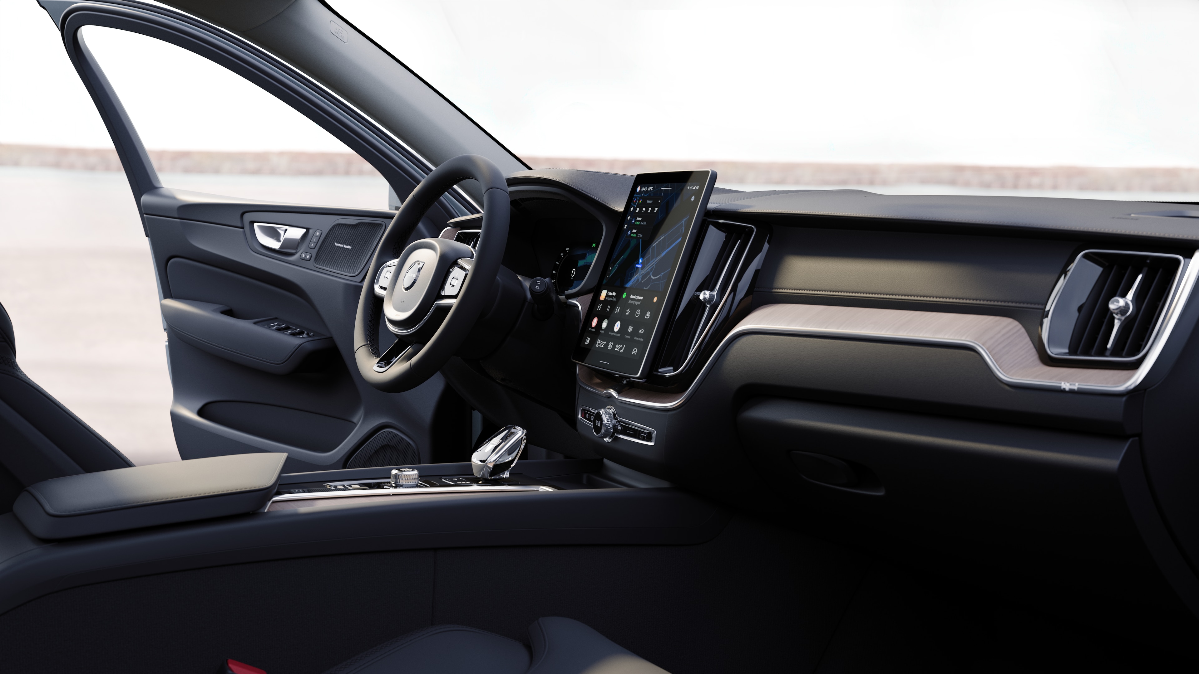 Інтер'єр автомобіля Volvo з панеллю приладів, кермом і центральною консоллю з цифровим дисплеєм на тлі відкритої дороги.