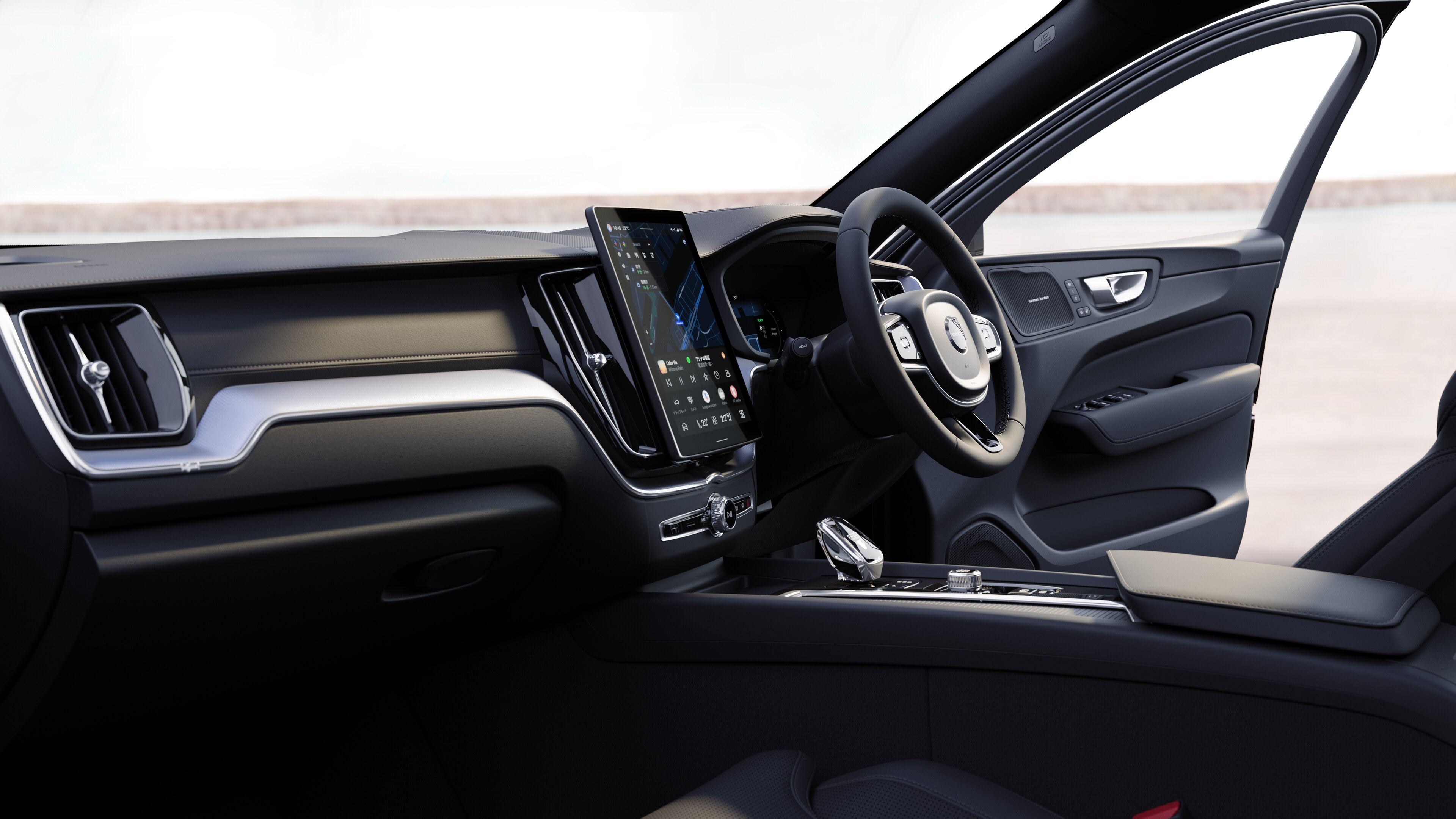 開けた路面を背景にダッシュボード、ステアリングホイール、センターコンソールをデジタルディスプレイで捉えたボルボ車のインテリア。