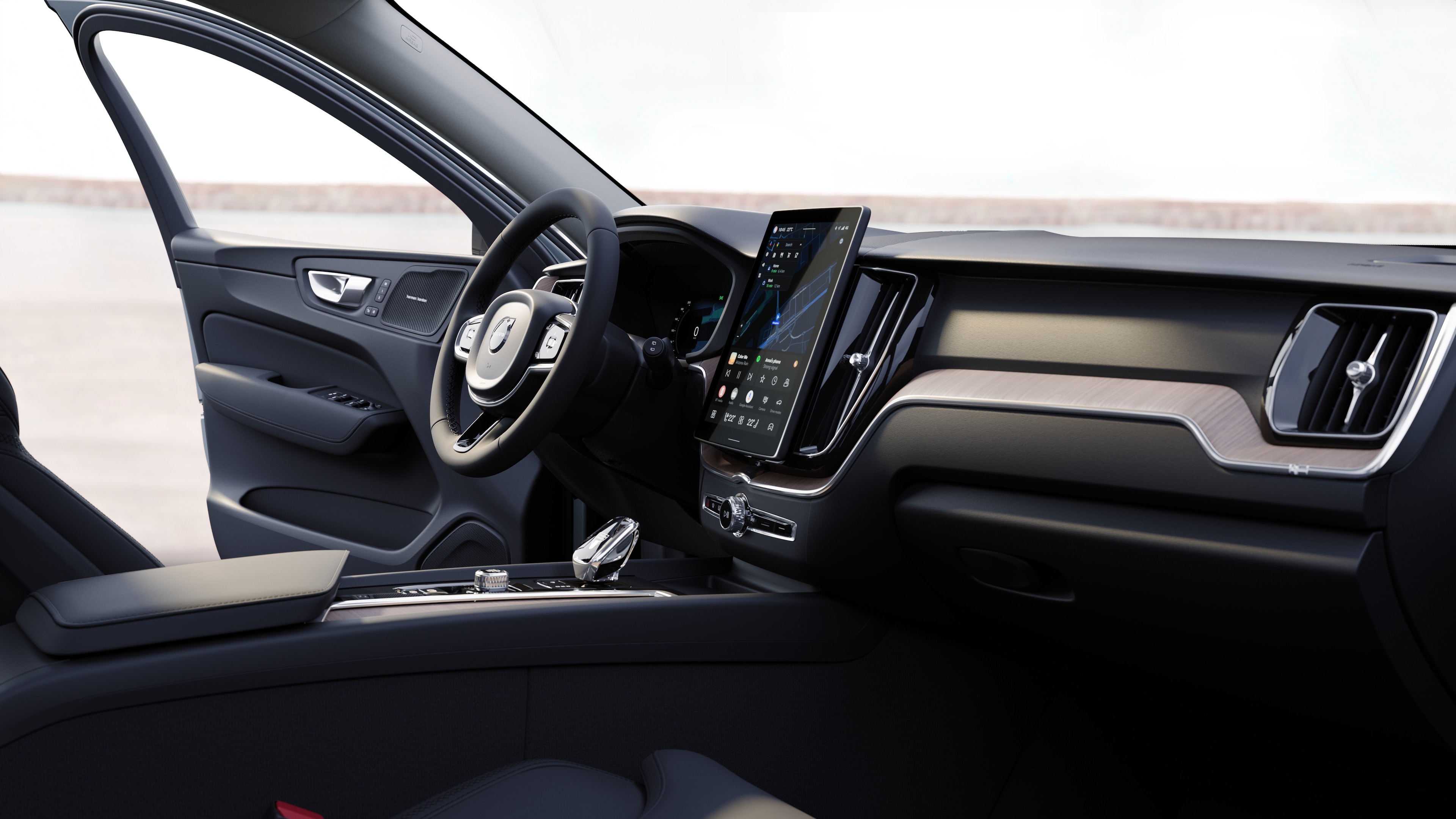 Volvo automašīnas salons ar informācijas paneli, stūri un centrālo konsoli ar digitālo displeju uz atvērta ceļa fona.