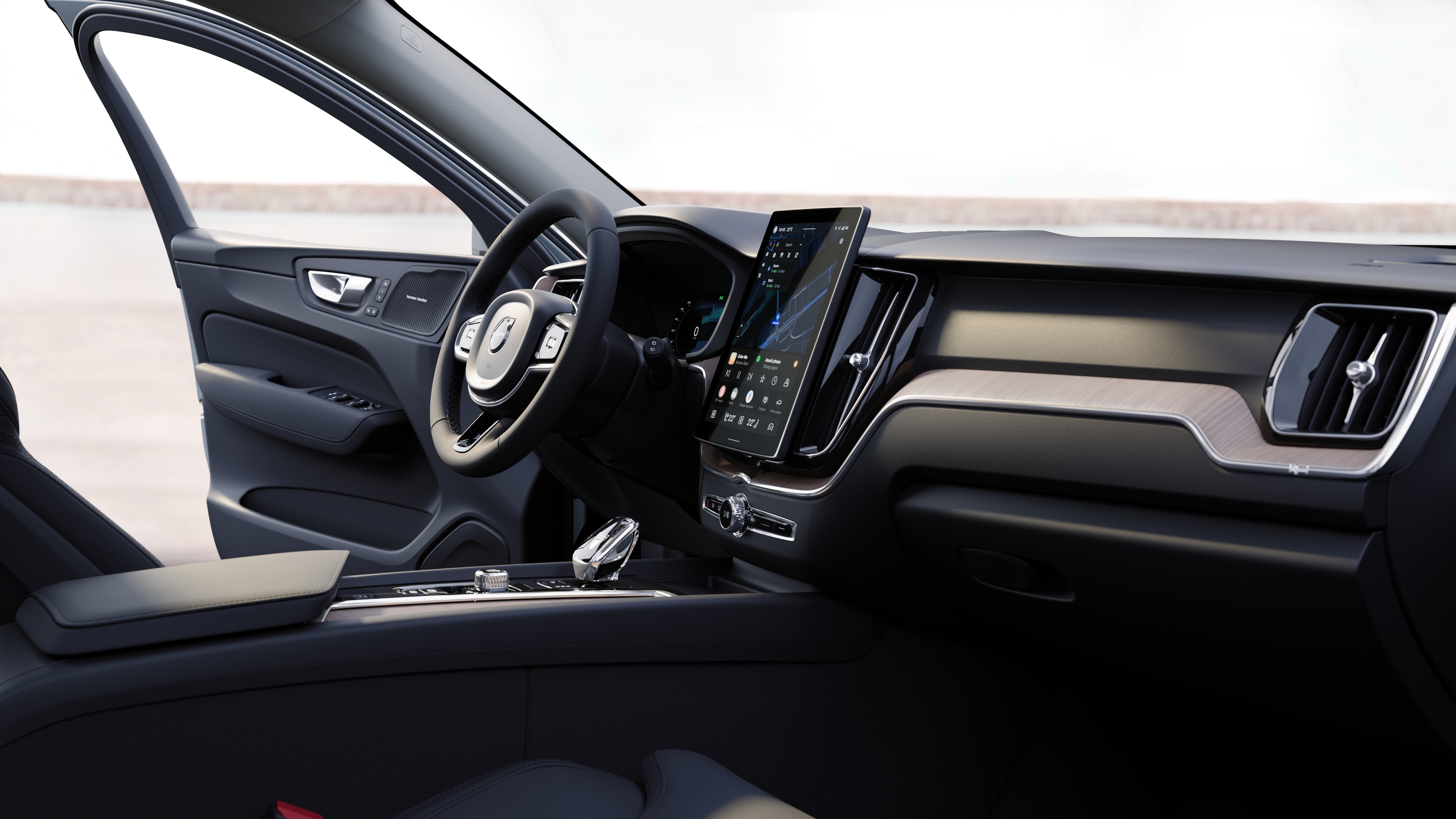 Intérieur d’une Volvo montrant le tableau de bord, le volant et la console centrale avec affichage numérique sur fond de route ouverte.