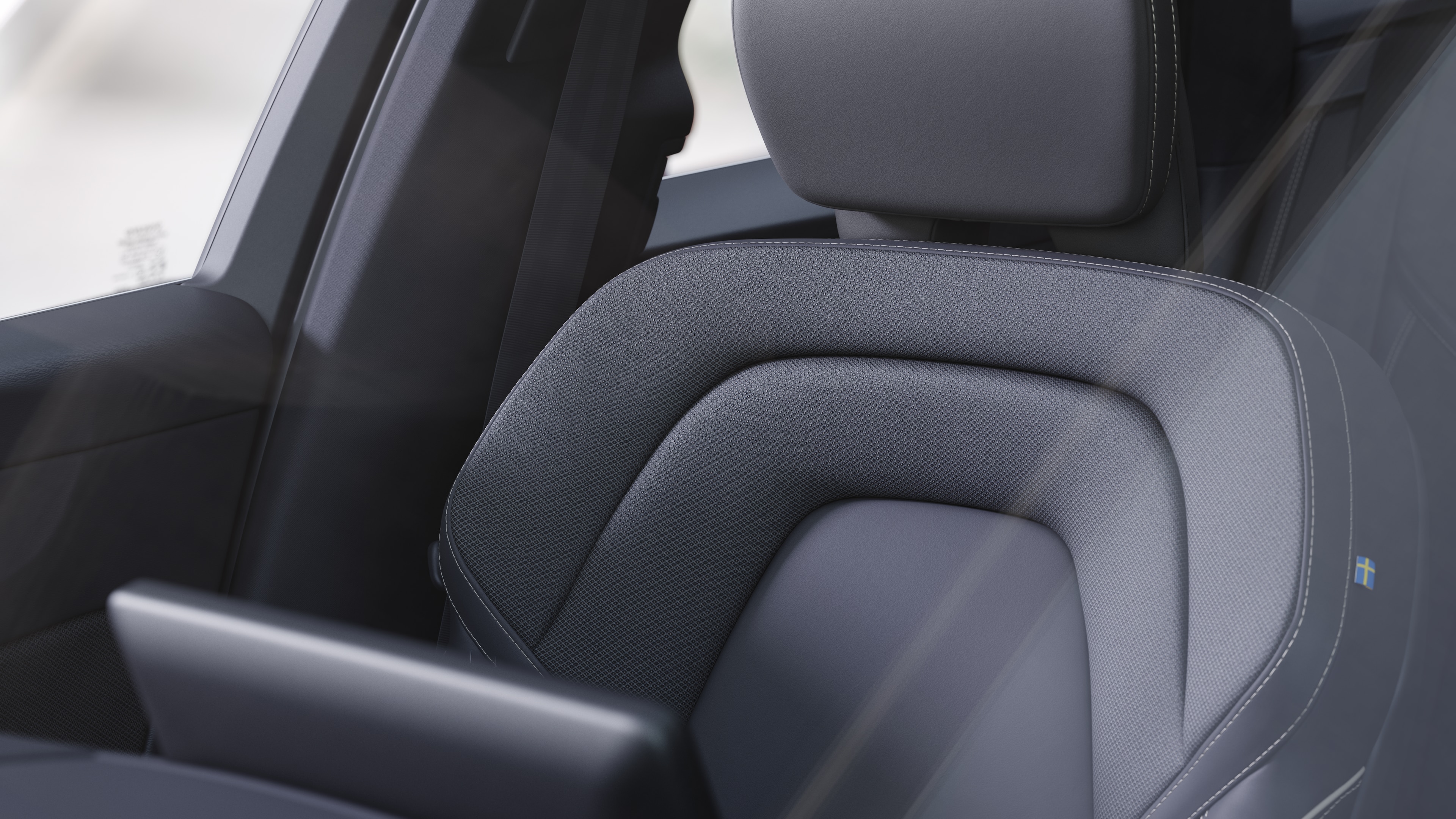 Innenraum eines Volvo mit Beifahrer- und Rücksitzen, Lenkrad, Armaturenbrett und Mittelkonsole vor einem schlichten Studiohintergrund.