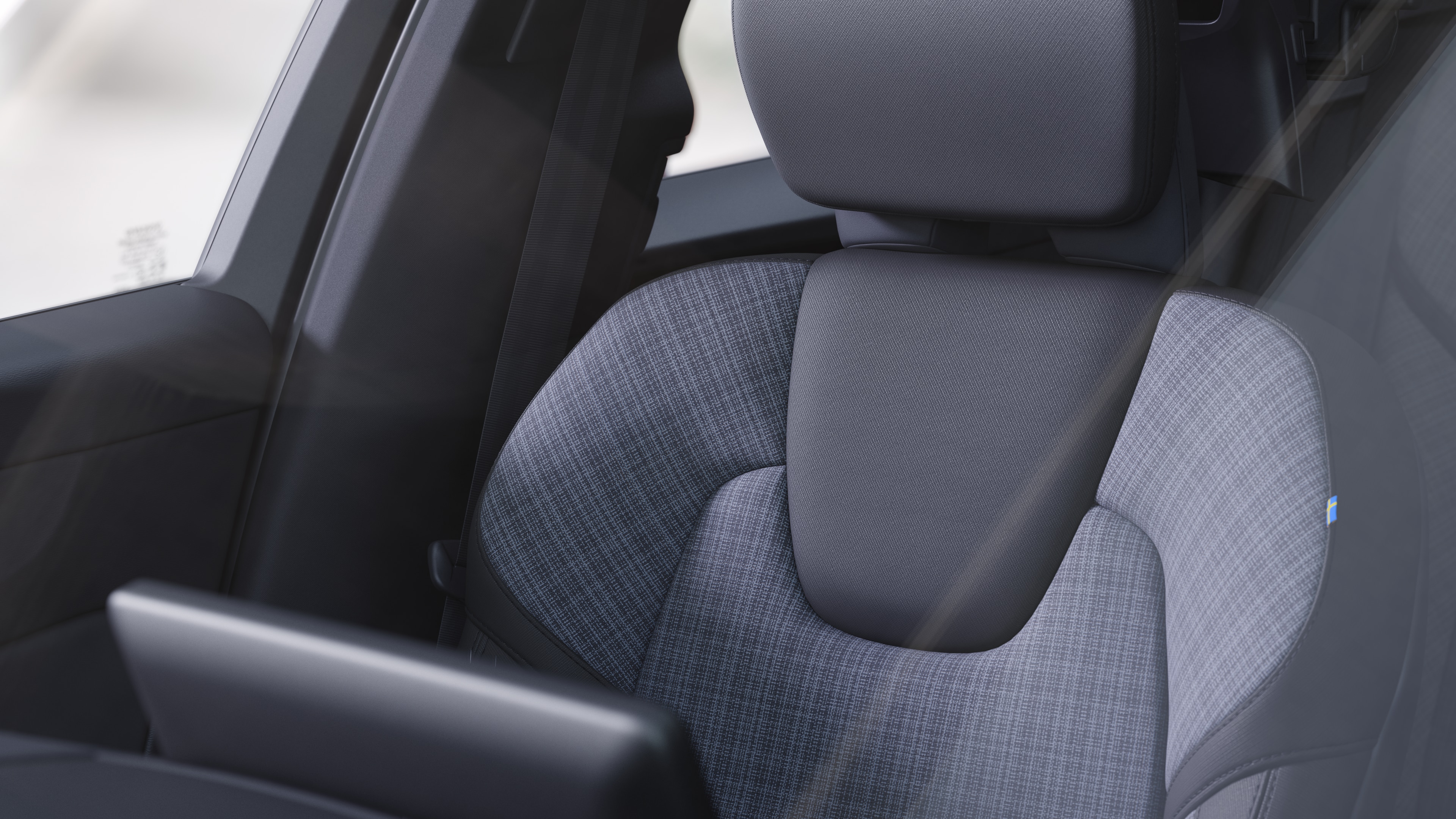 Interiér vozu Volvo zobrazující přední a zadní sedadla spolujezdce, volant, palubní desku a středovou konzolu na pozadí jednoduchého studia.