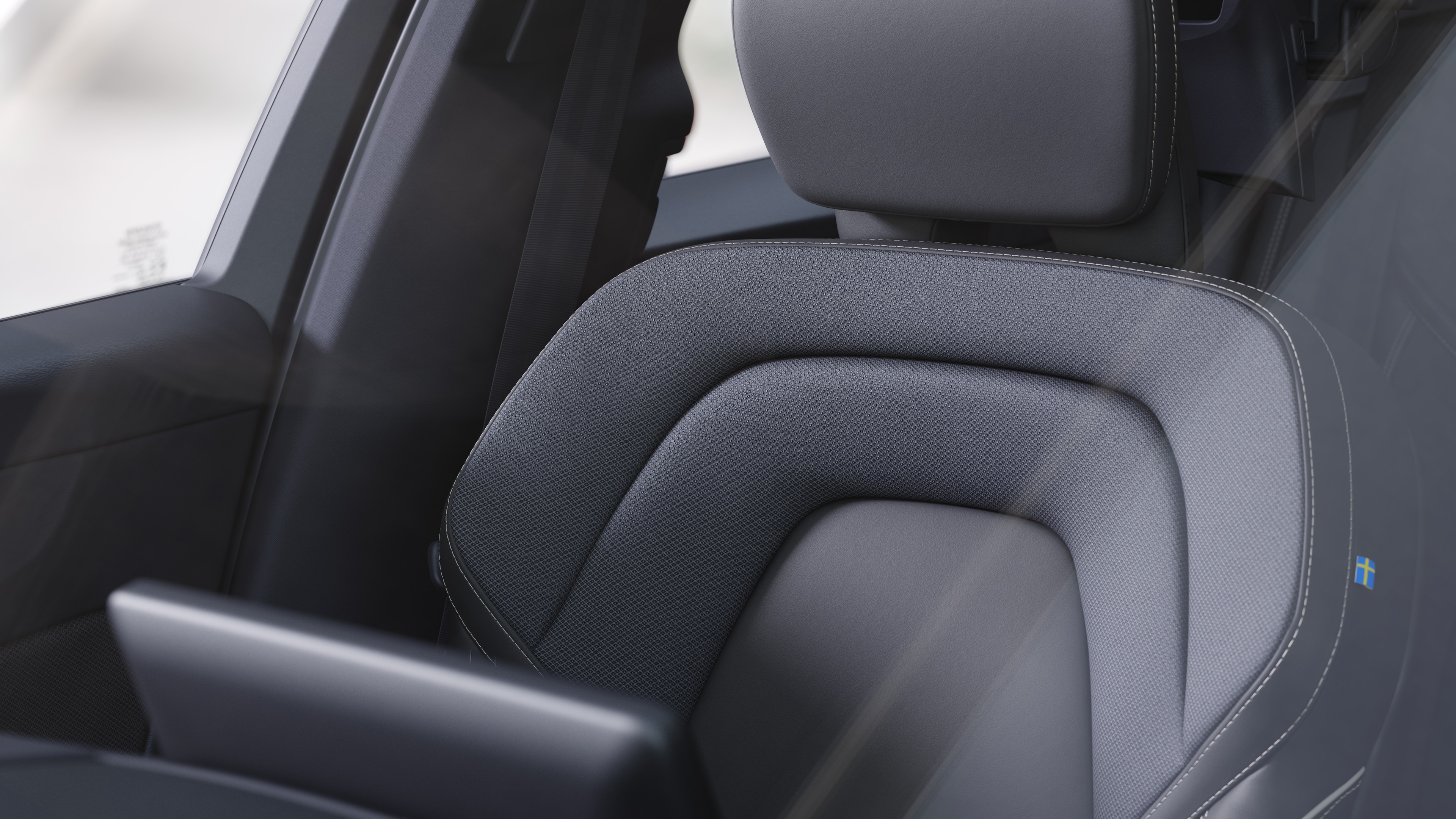 Innenraum eines Volvo mit Beifahrer- und Rücksitzen, Lenkrad, Armaturenbrett und Mittelkonsole vor einem schlichten Studiohintergrund.