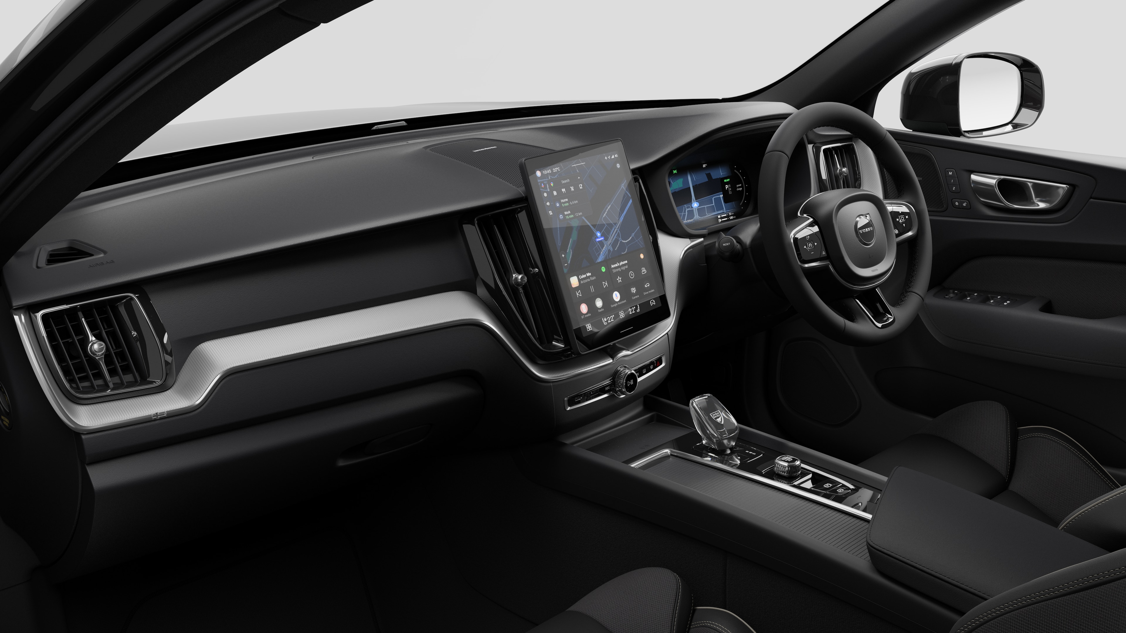 Interior view of a Volvo car showing the dashboard, steering wheel, center console, and digital display screen in a plain studio background.