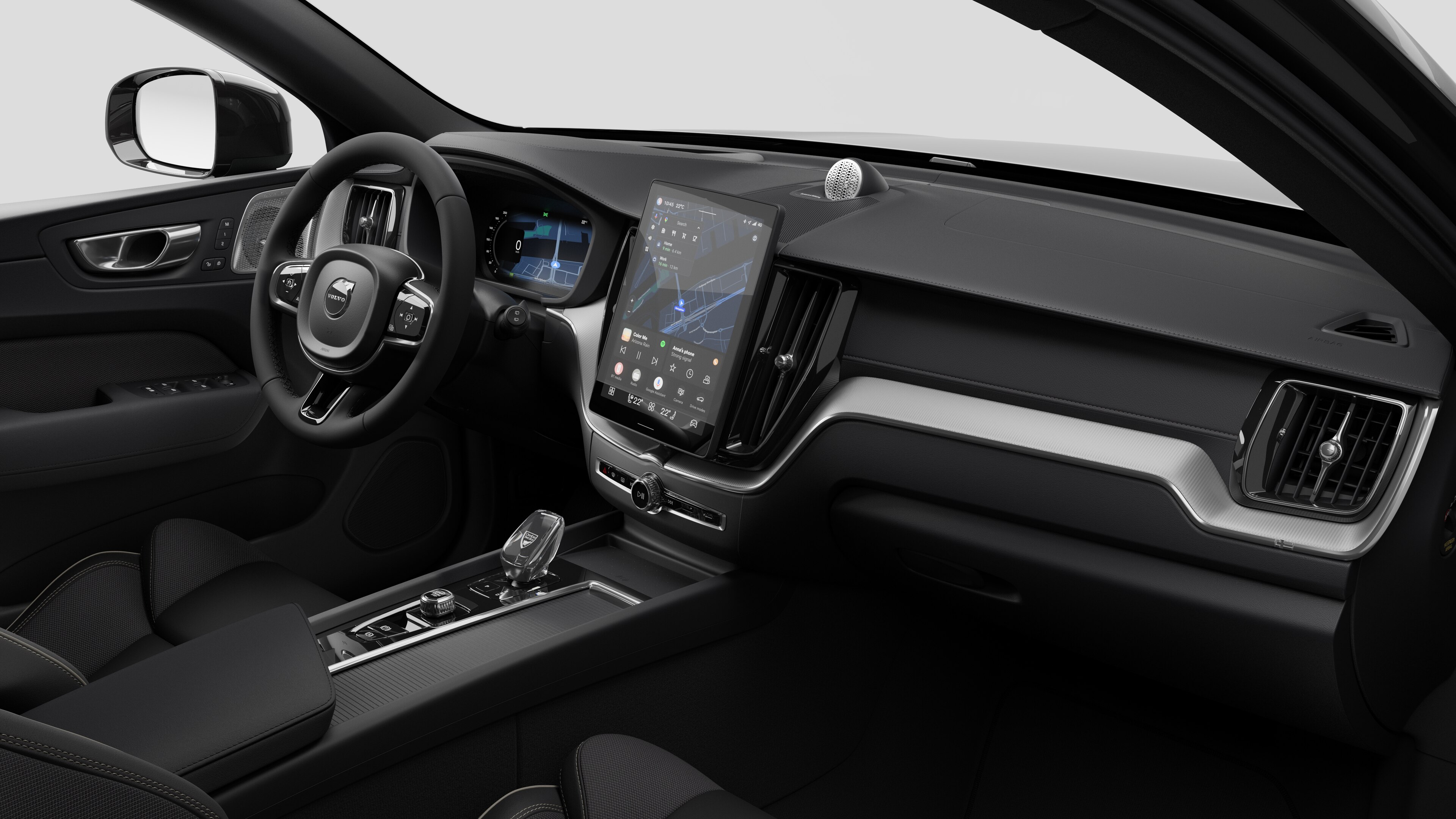 Interior view of a Volvo car showing the dashboard, steering wheel, center console, and digital display screen in a plain studio background.