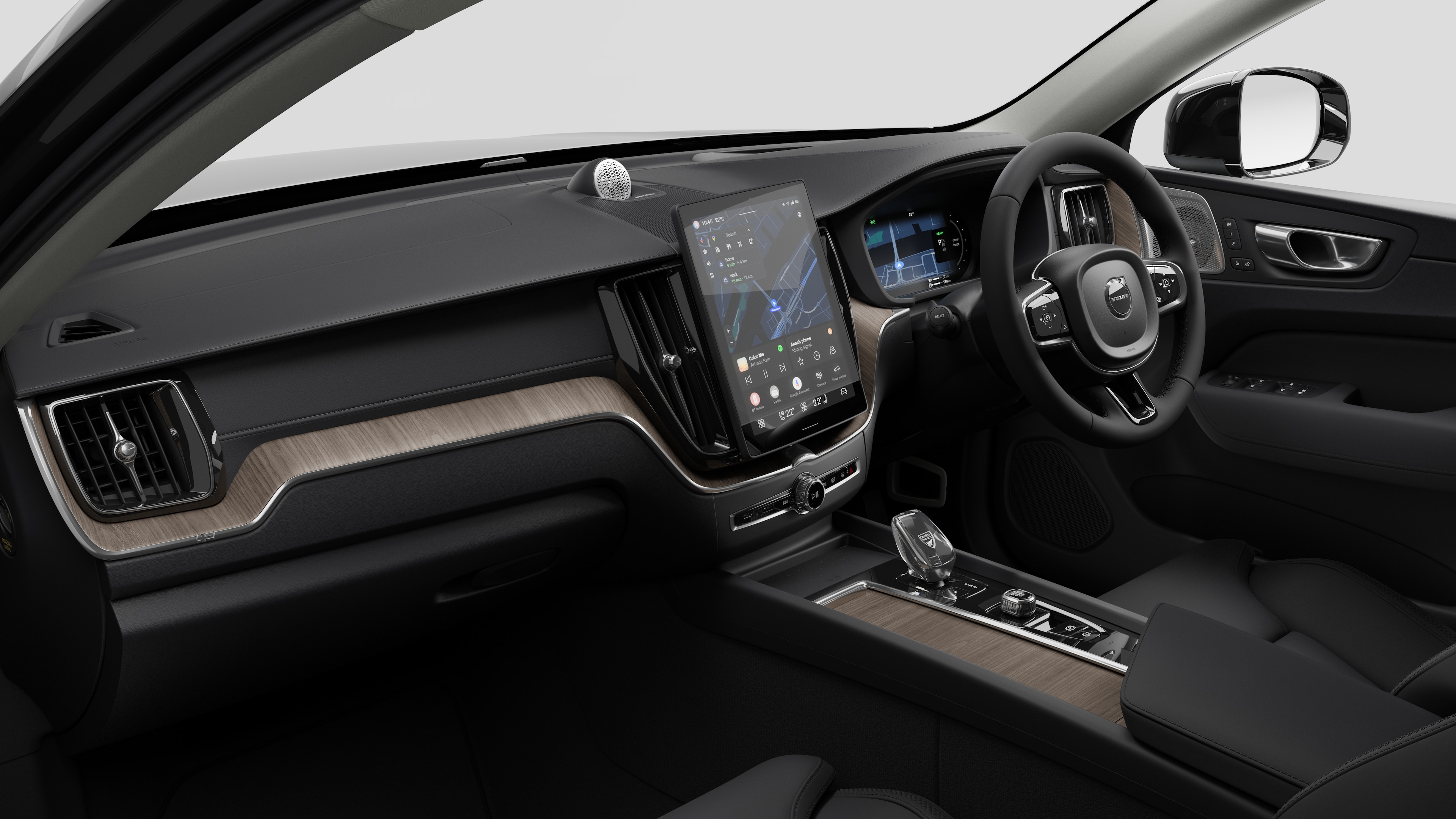 Interior view of a Volvo car showing the dashboard, steering wheel, center console, and digital display screen in a plain studio background.