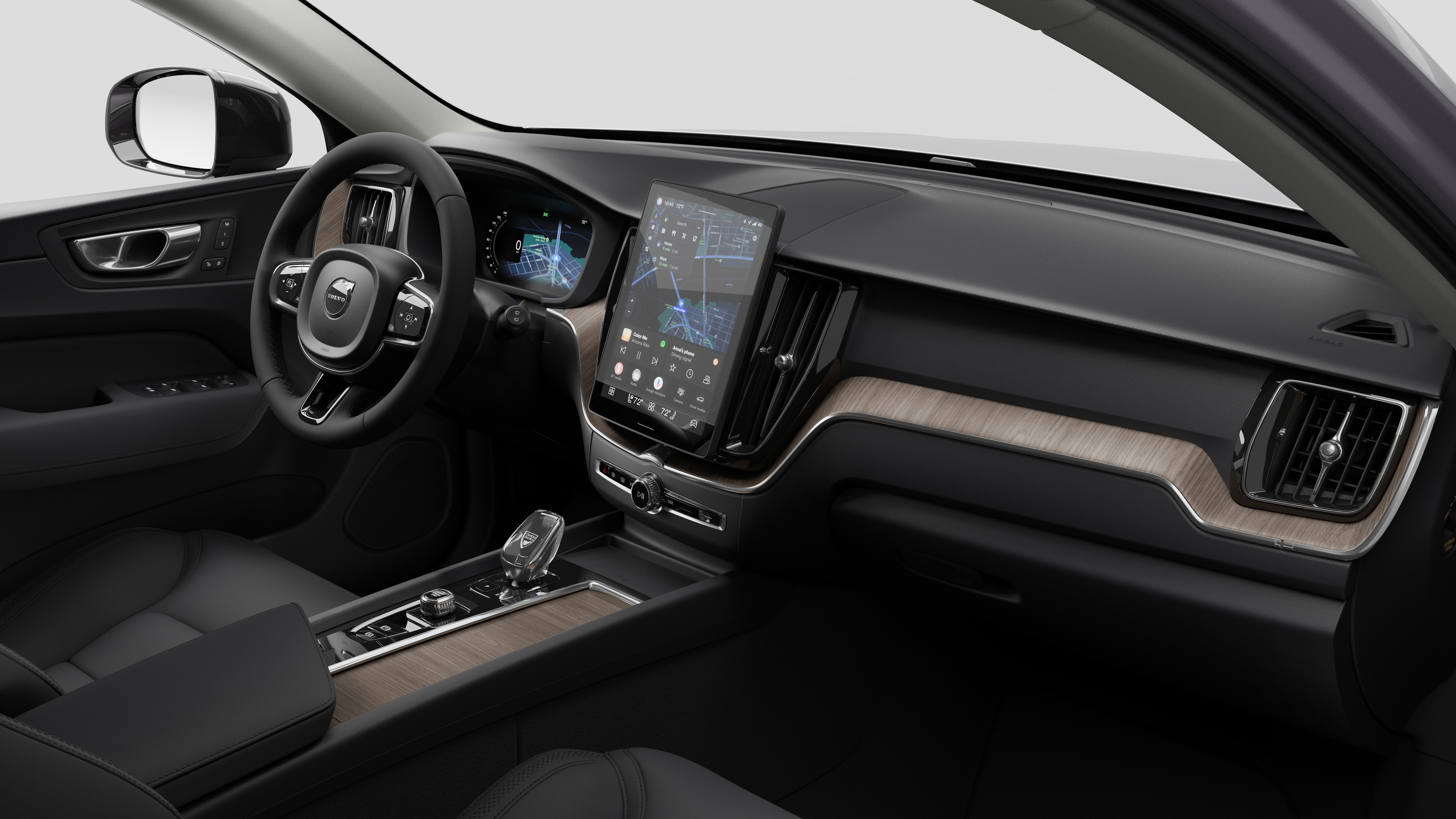 Interior view of a Volvo car showing the dashboard, steering wheel, center console, and digital display screen in a plain studio background.
