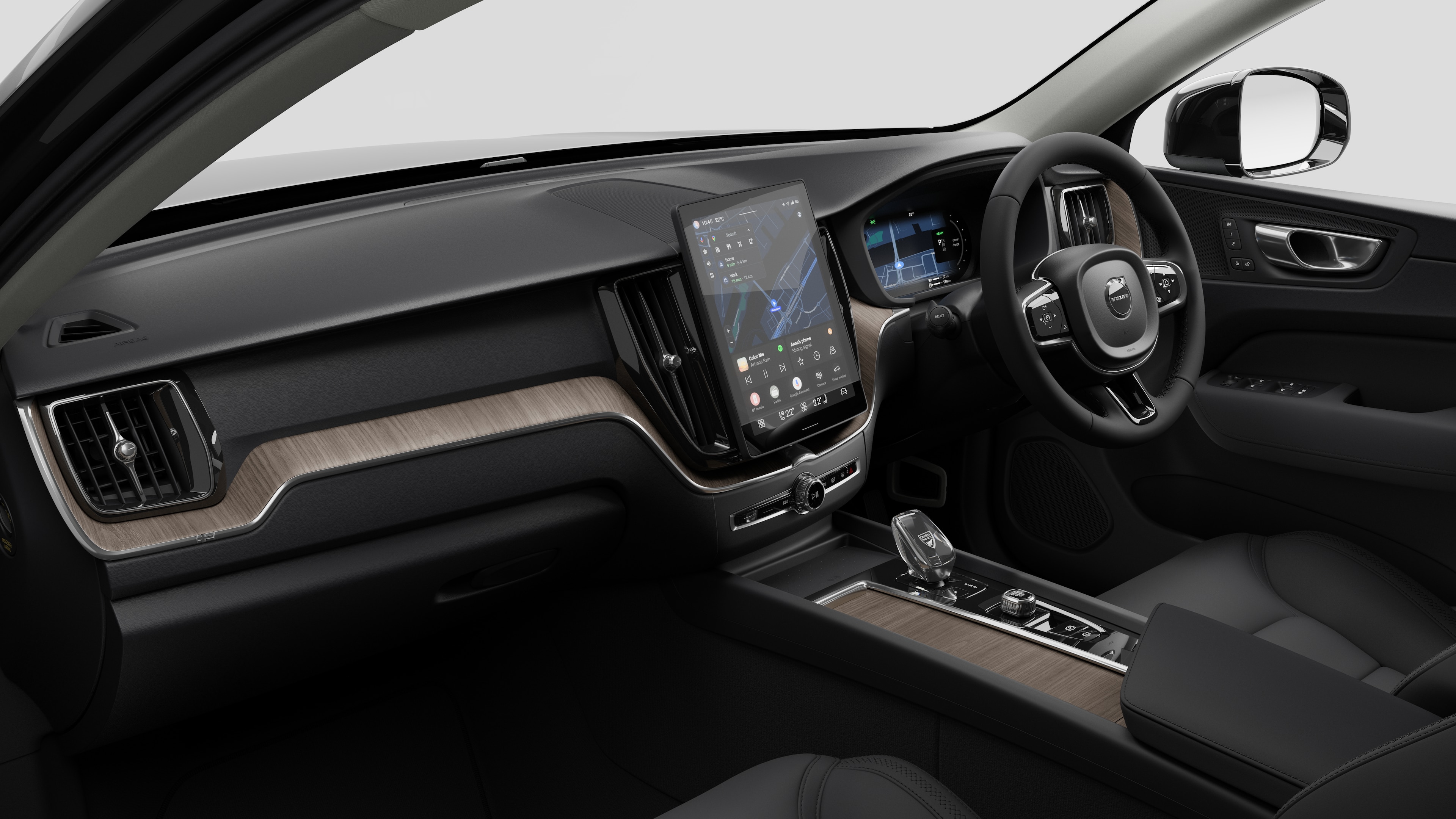 Interior view of a Volvo car showing the dashboard, steering wheel, center console, and digital display screen in a plain studio background.