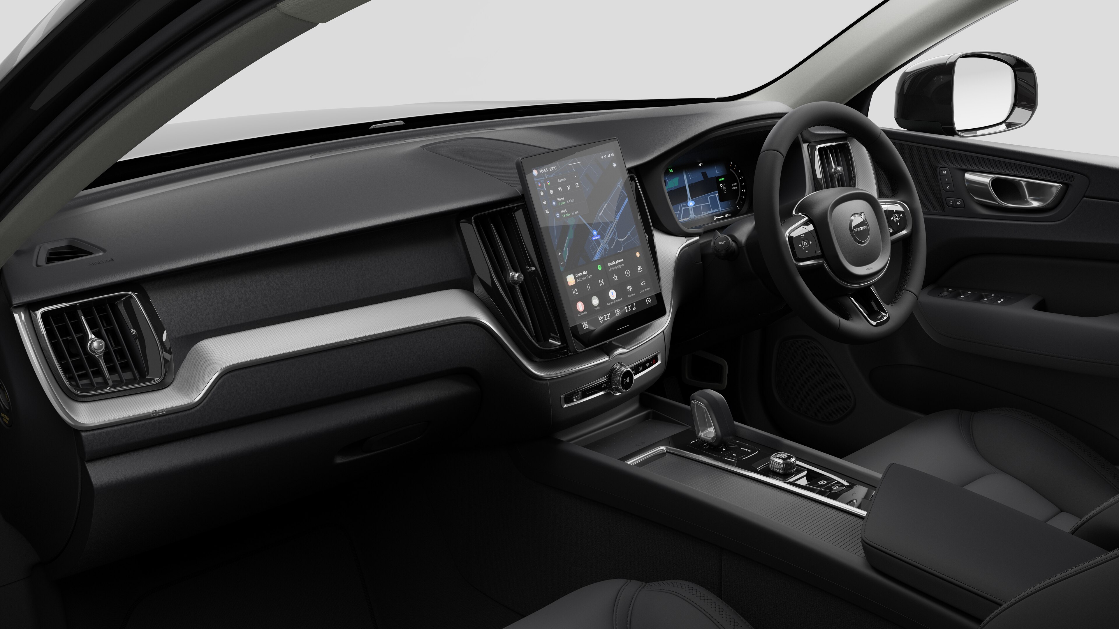 Interior view of a Volvo car showing the dashboard, steering wheel, center console, and digital display screen in a plain studio background.
