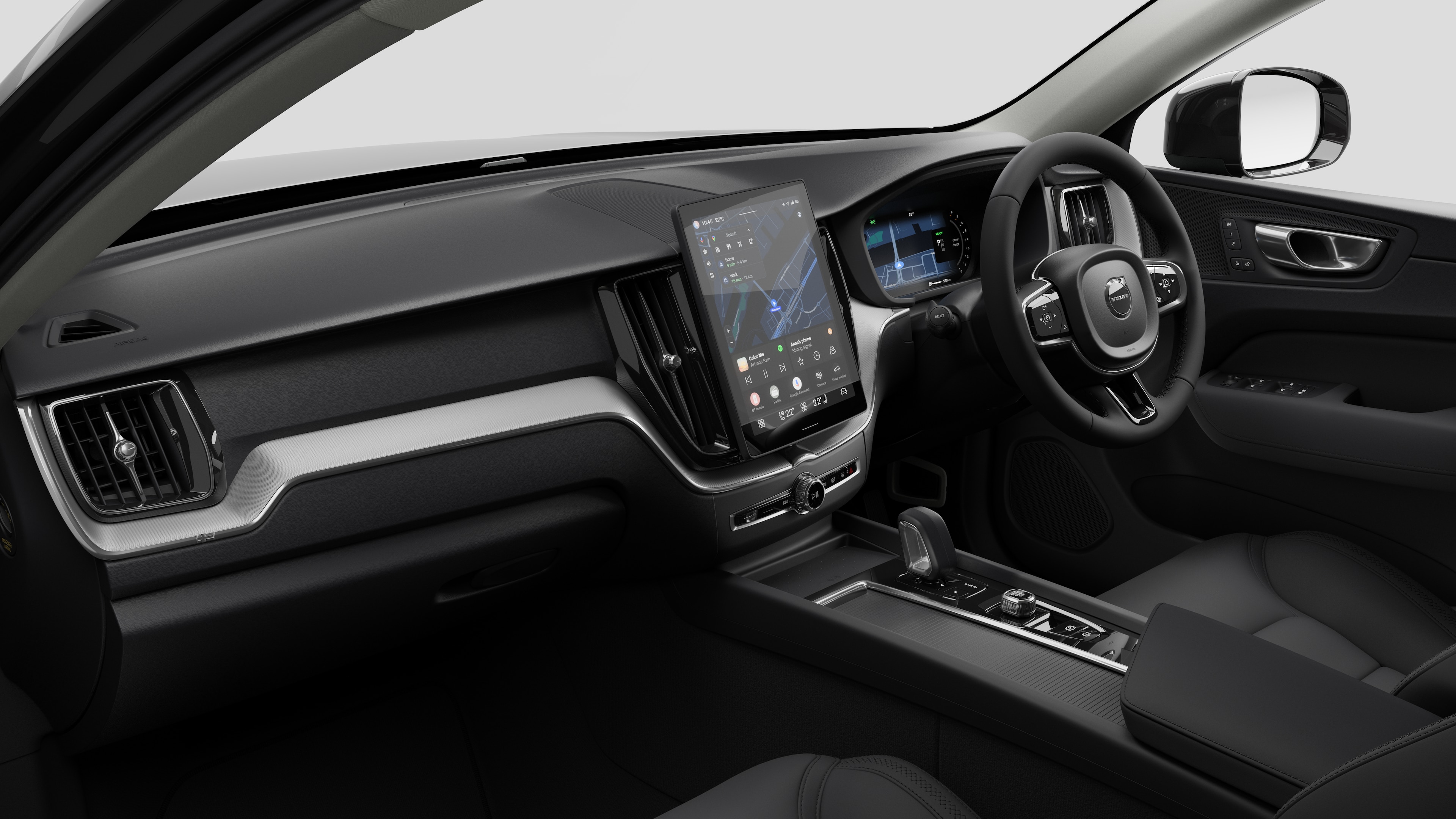 Interior view of a Volvo car showing the dashboard, steering wheel, center console, and digital display screen in a plain studio background.