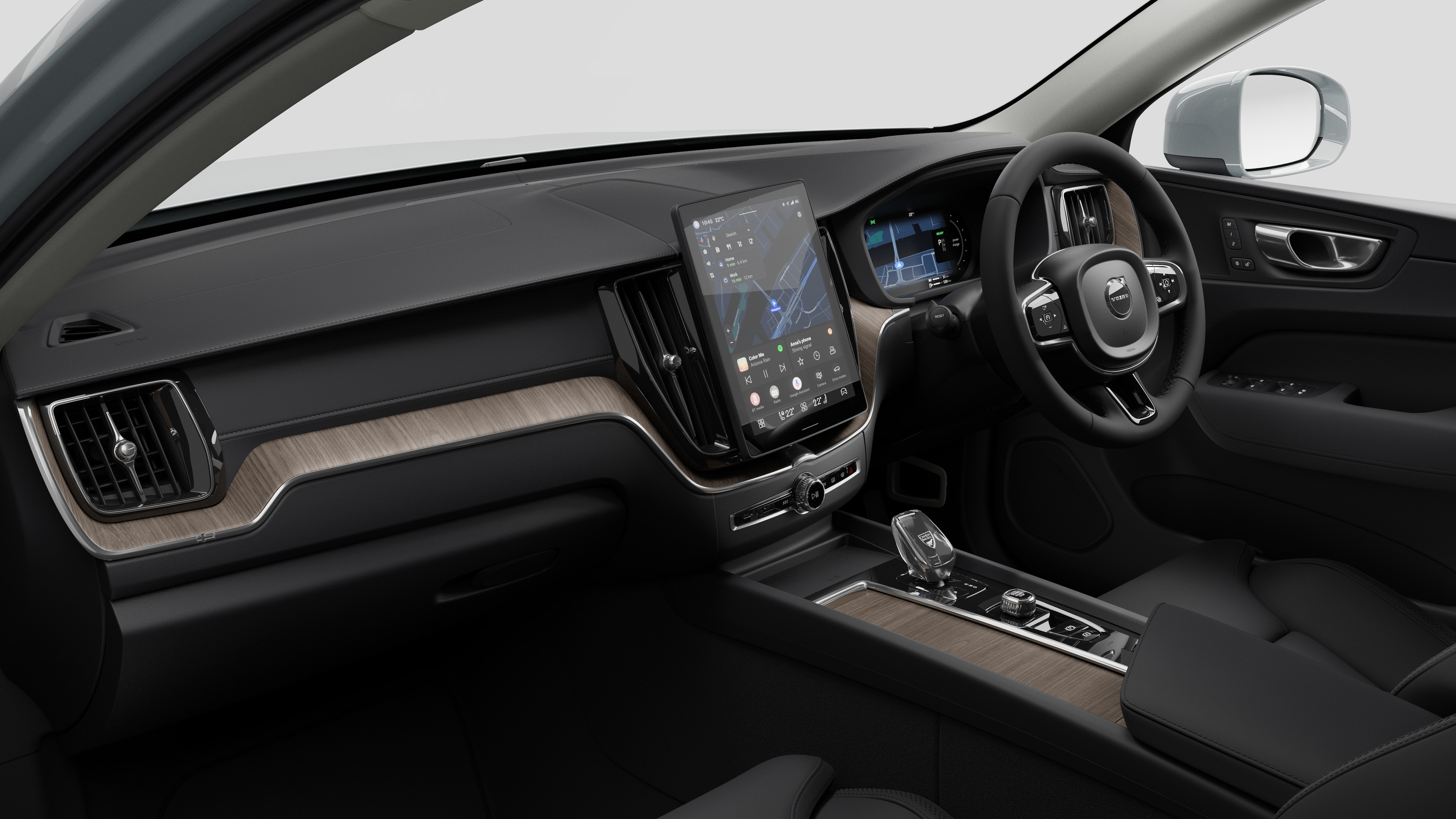 Interior view of a Volvo car showing the dashboard, steering wheel, center console, and digital display screen in a plain studio background.