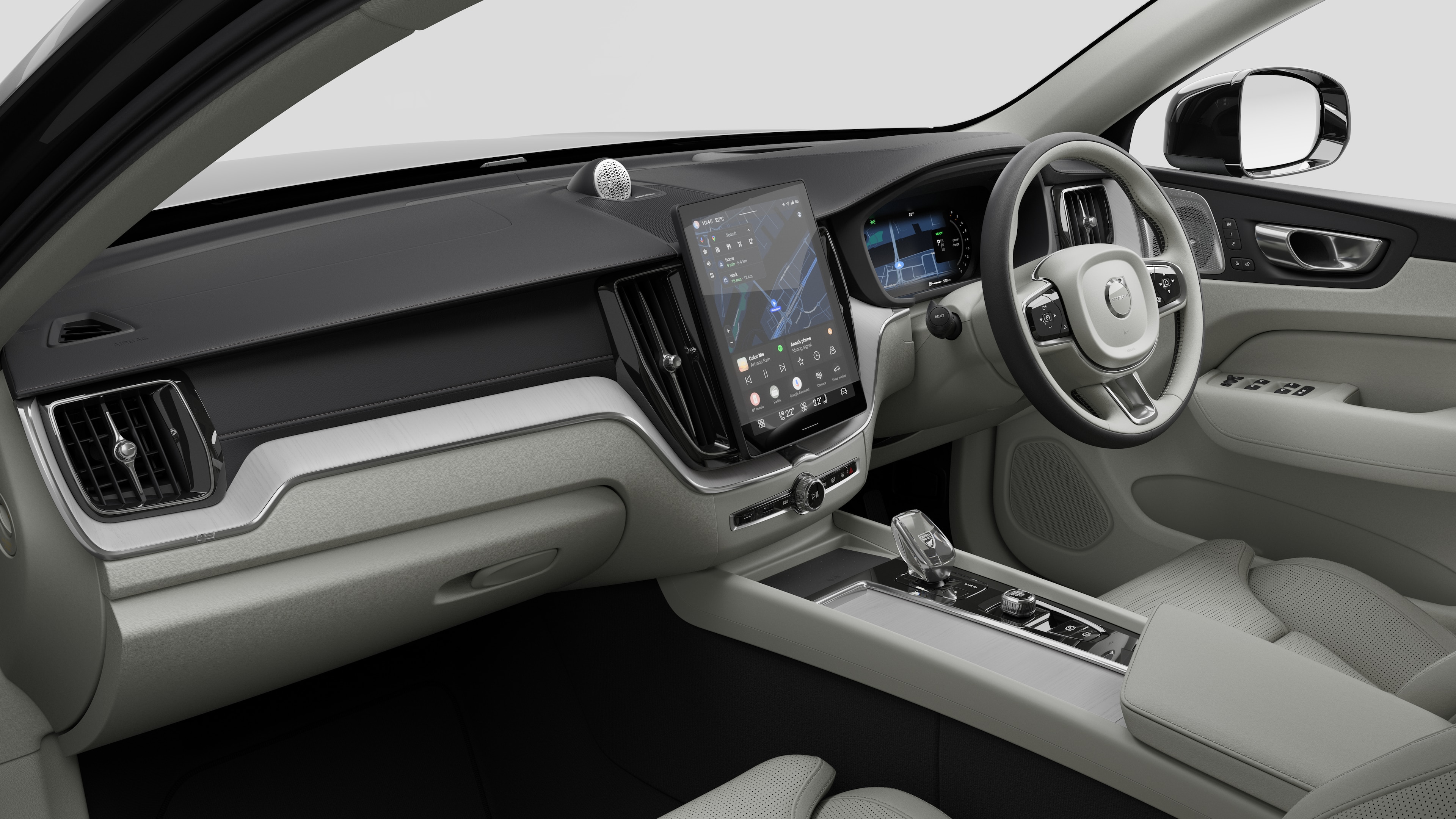 Interior view of a Volvo car showing the dashboard, steering wheel, center console, and digital display screen in a plain studio background.
