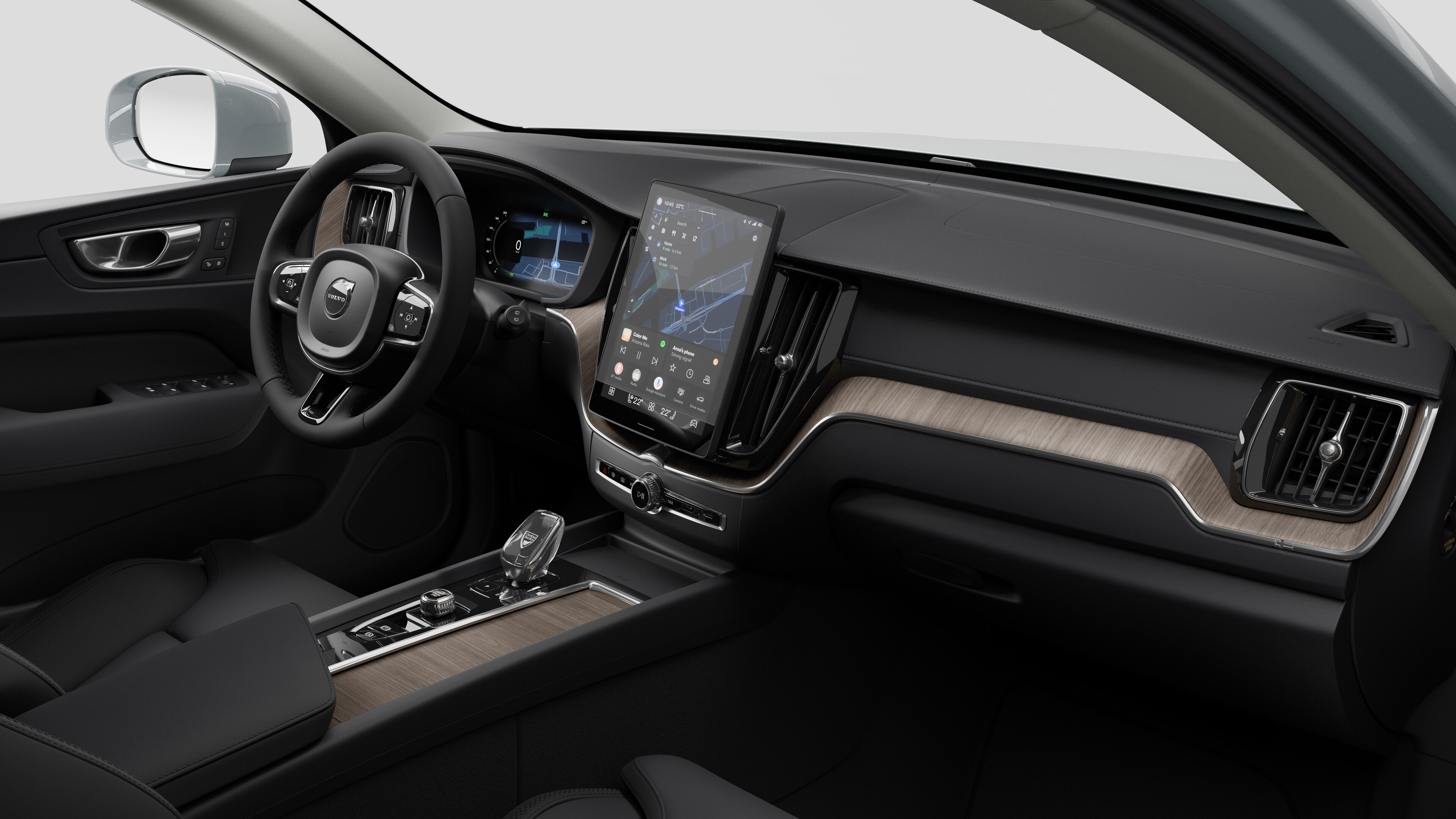 Interior view of a Volvo car showing the dashboard, steering wheel, center console, and digital display screen in a plain studio background.