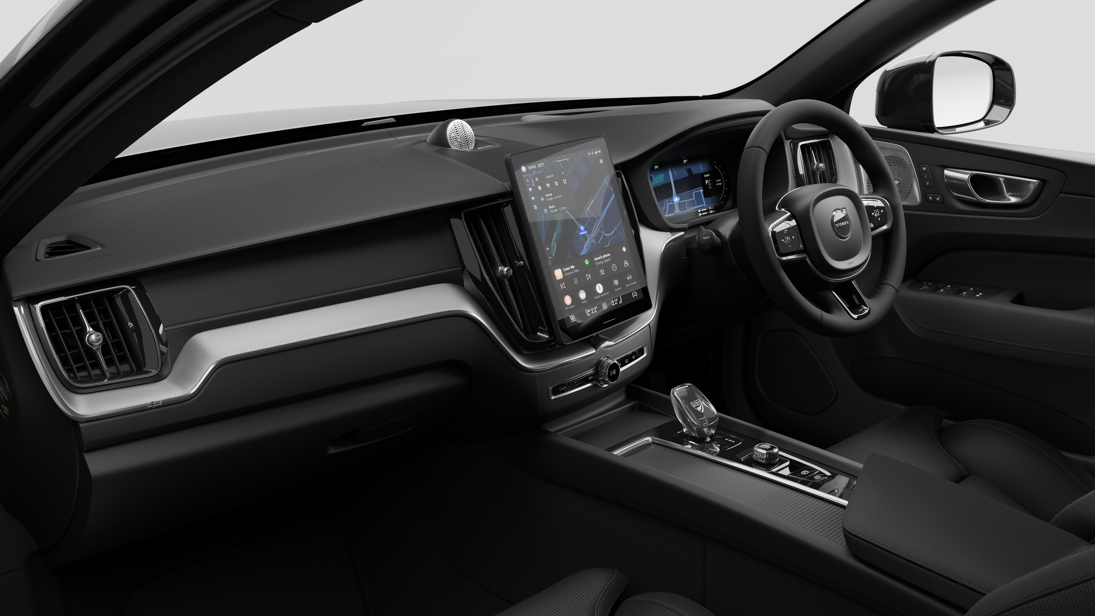 Interior view of a Volvo car showing the dashboard, steering wheel, center console, and digital display screen in a plain studio background.