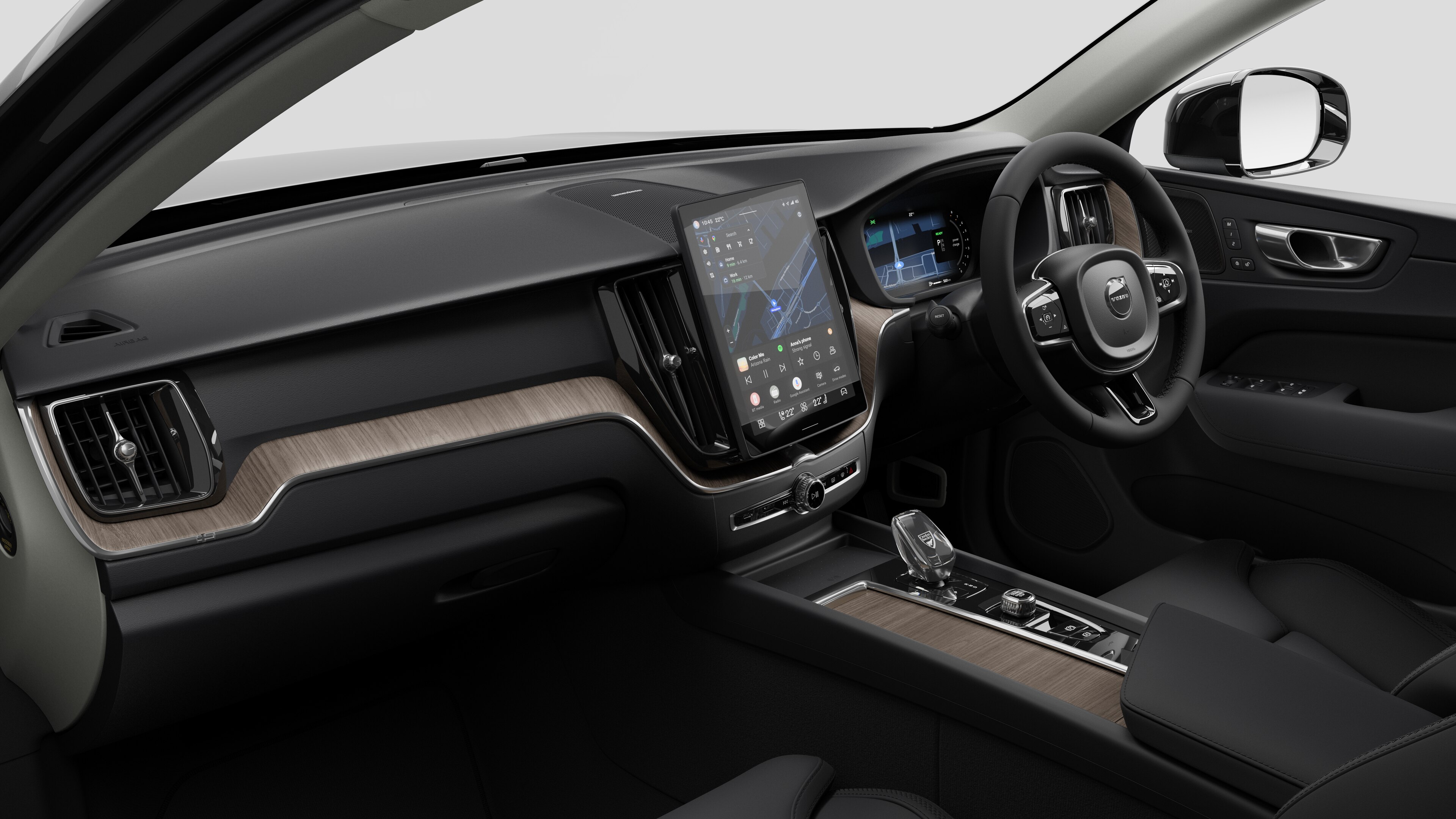 Interior view of a Volvo car showing the dashboard, steering wheel, center console, and digital display screen in a plain studio background.